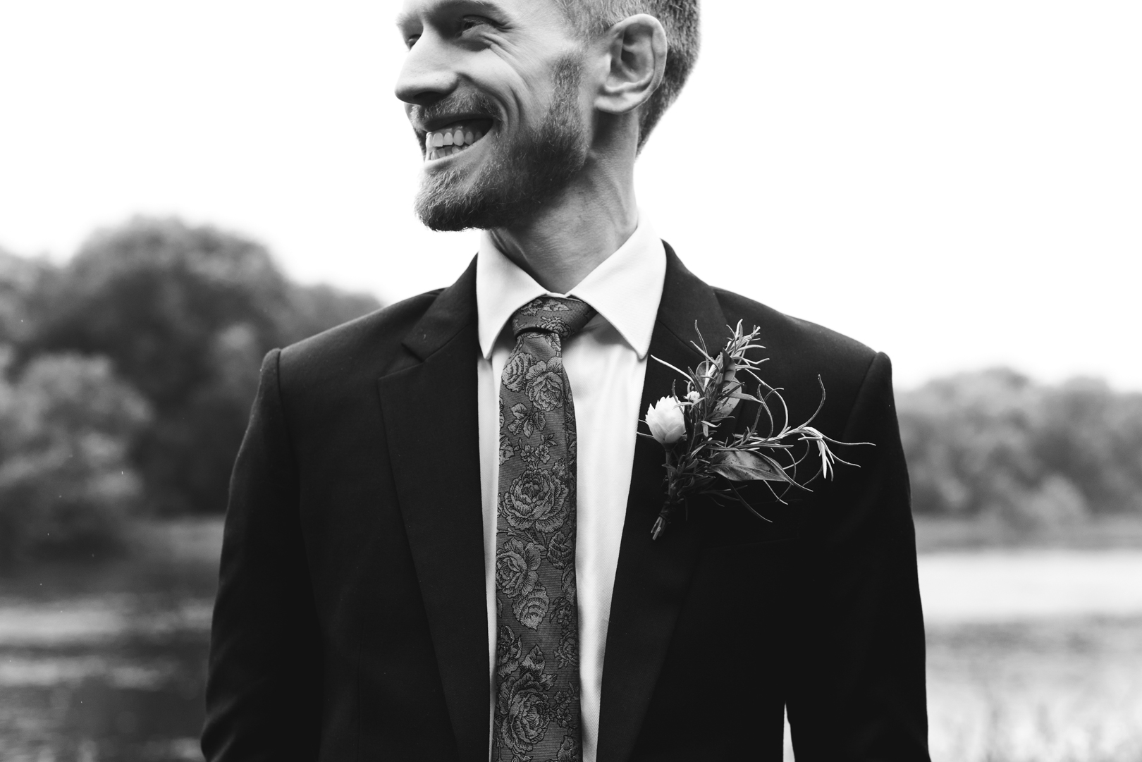 groom smiling looking off the distance in black and white