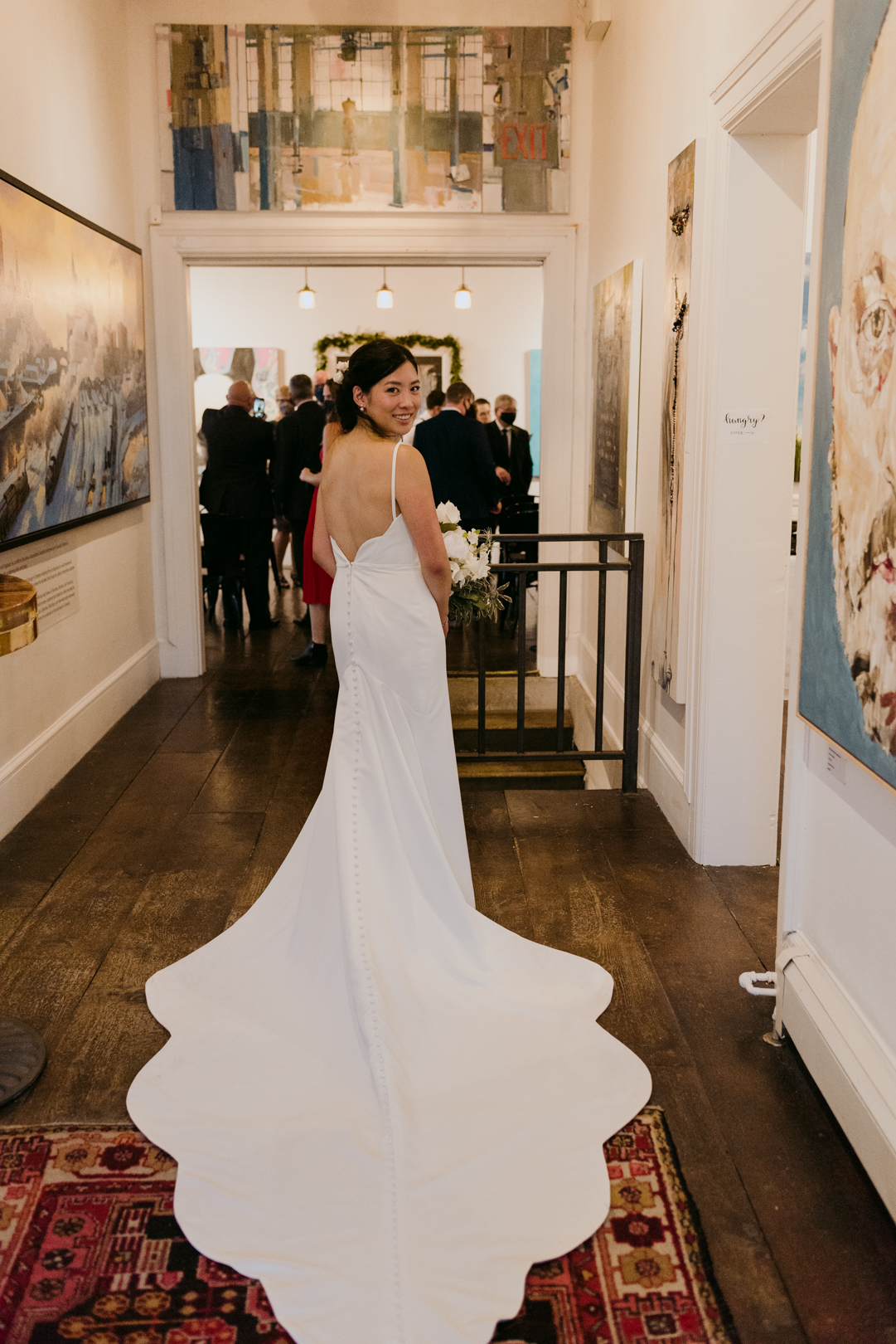 bride standing in the hallway with train of her dress spread out at Orange Art Gallery