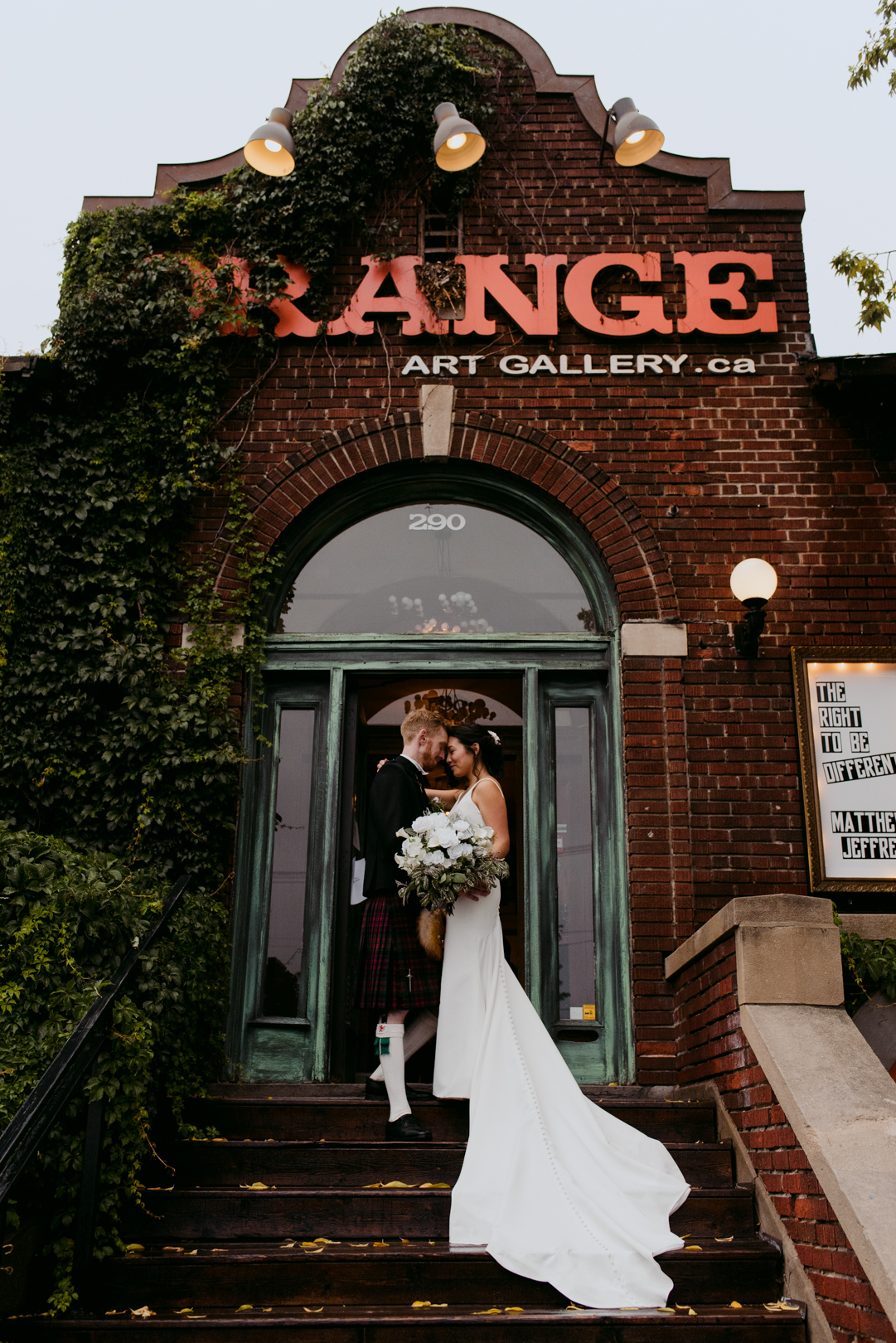 bride and groom standing on steps of the Orange Art Gallery with bride's train down the steps