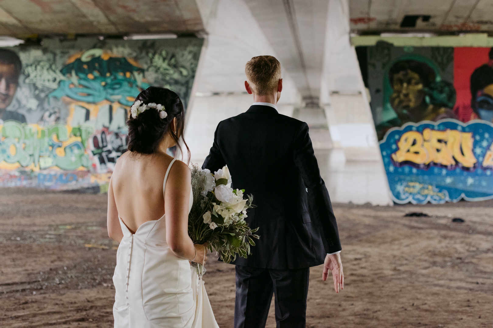 bride and groom first look underneath a bridge with graffiti
