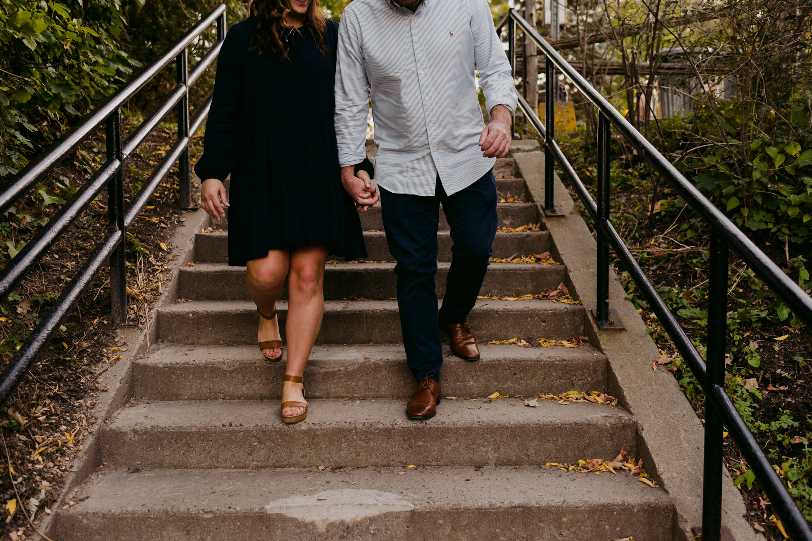 engaged couple walking down the stairs by Watson's Mill in Manotick