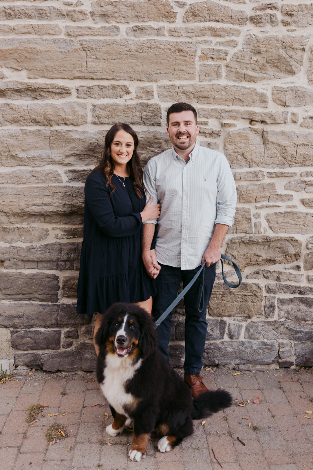 engagement photos with dog against brick wall