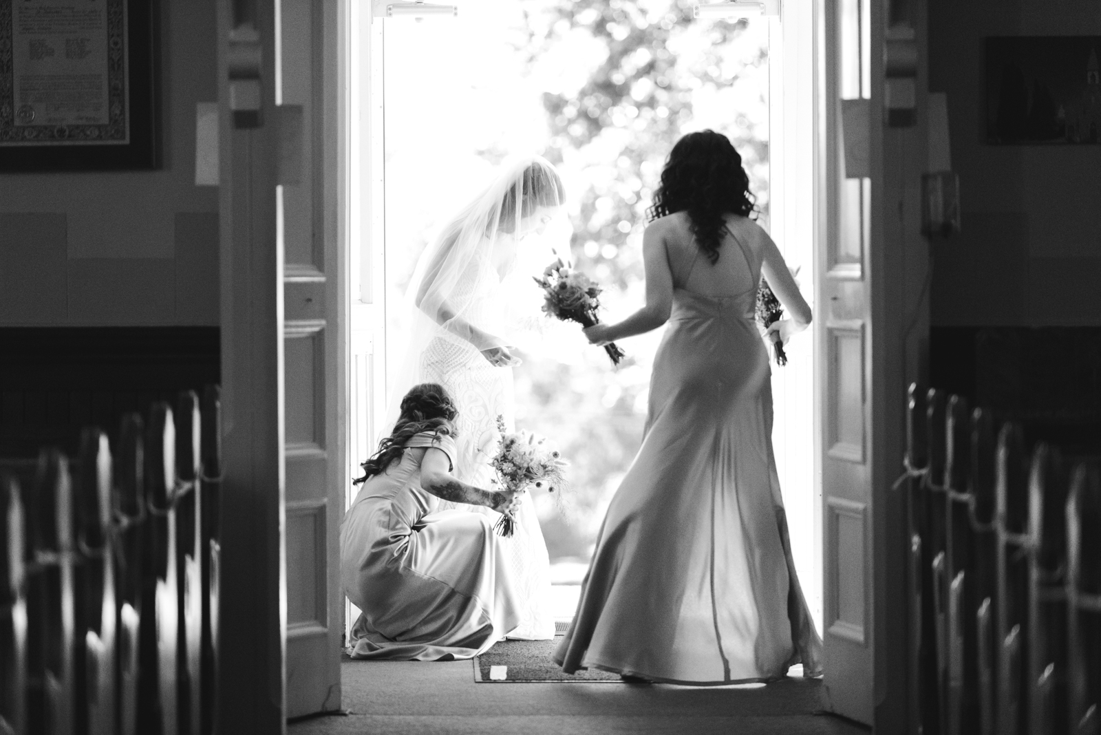 bridesmaids helping with bride's dress outside the church doors