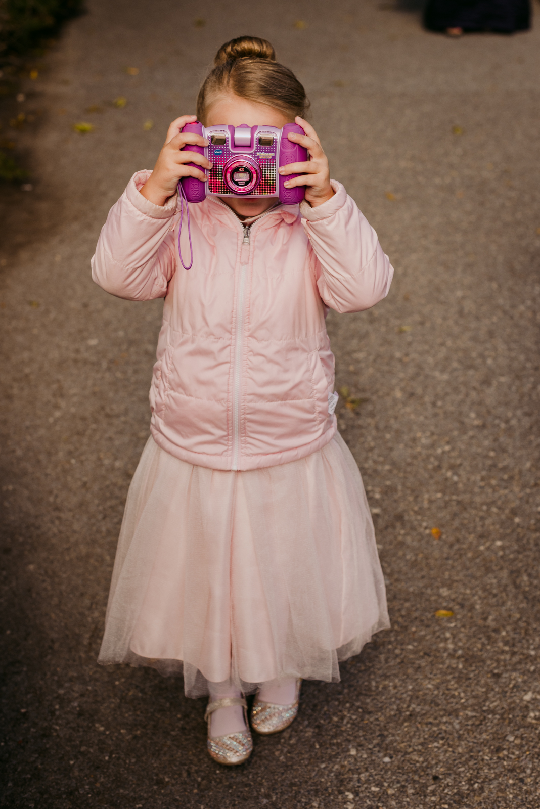 flower girl holding pink camera up to her eye