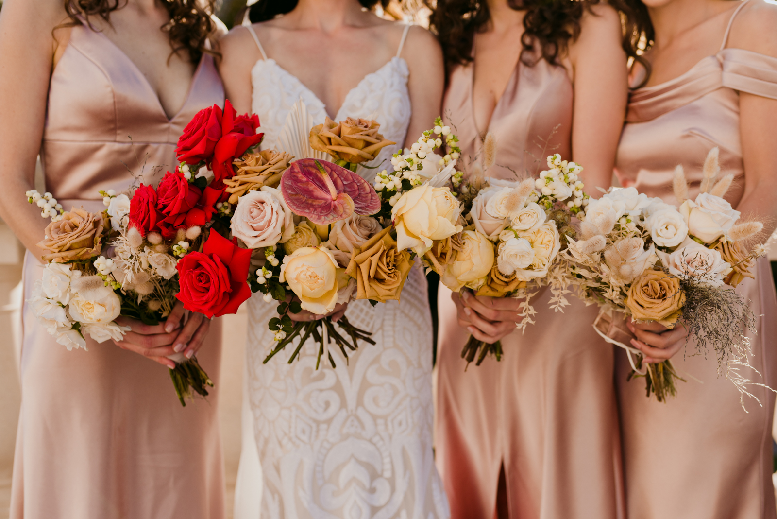 bride and bridesmaids in rose gold holding bouquet of roses
