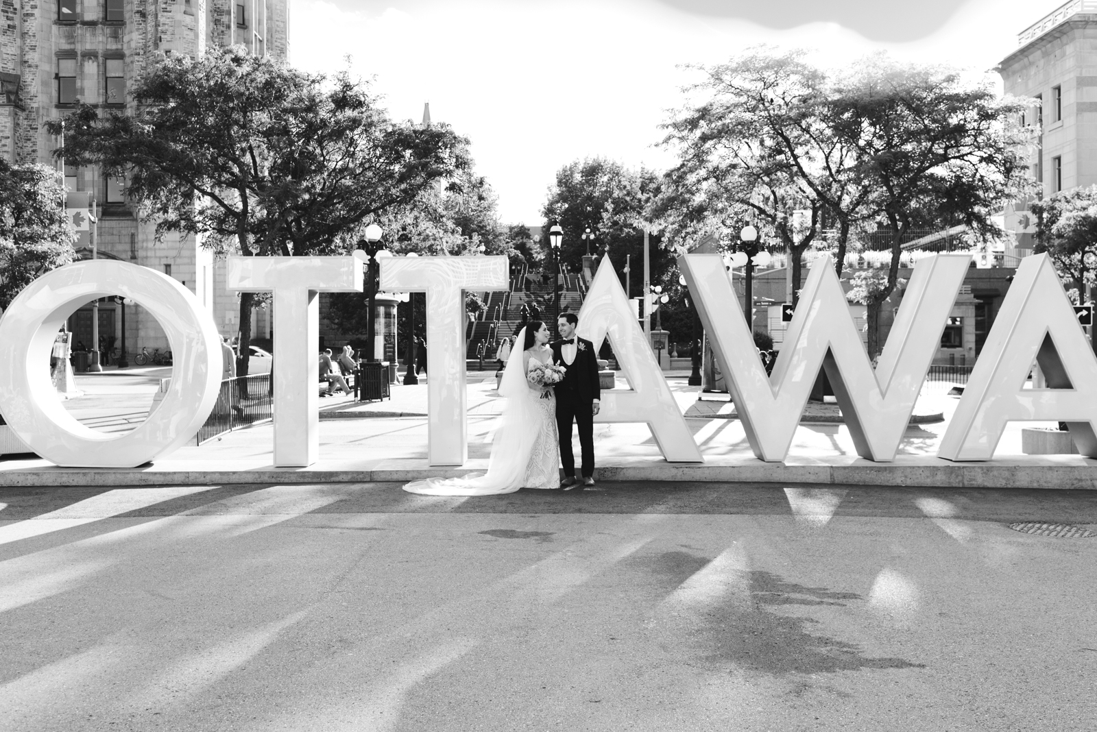 bride and groom standing in front of Ottawa sign in the byward market in black and white
