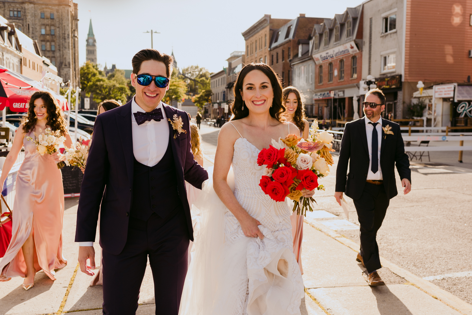 bride and groom walking through the byward market with their wedding party on a sunny day