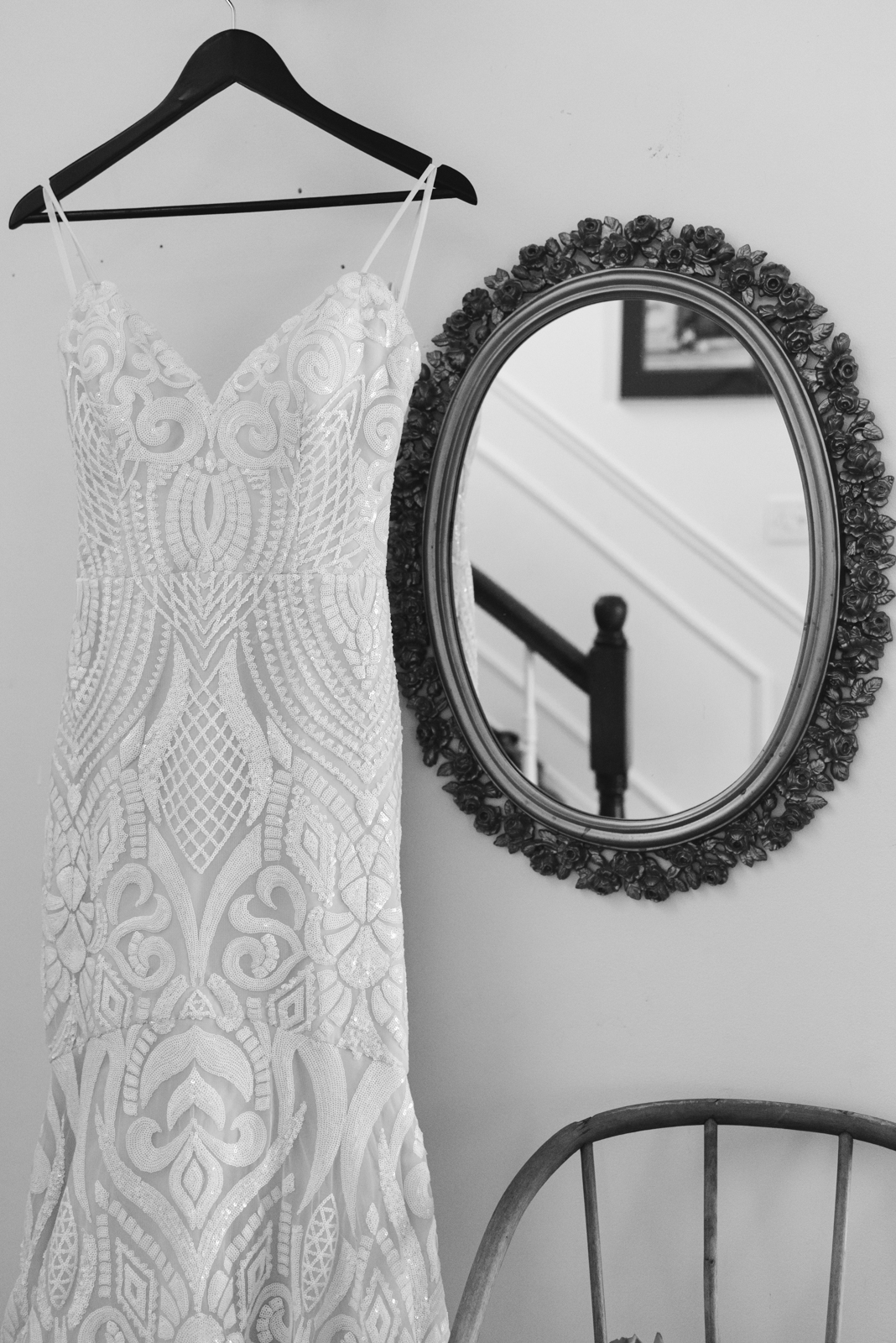wedding dress hanging next to vintage mirror in black and white