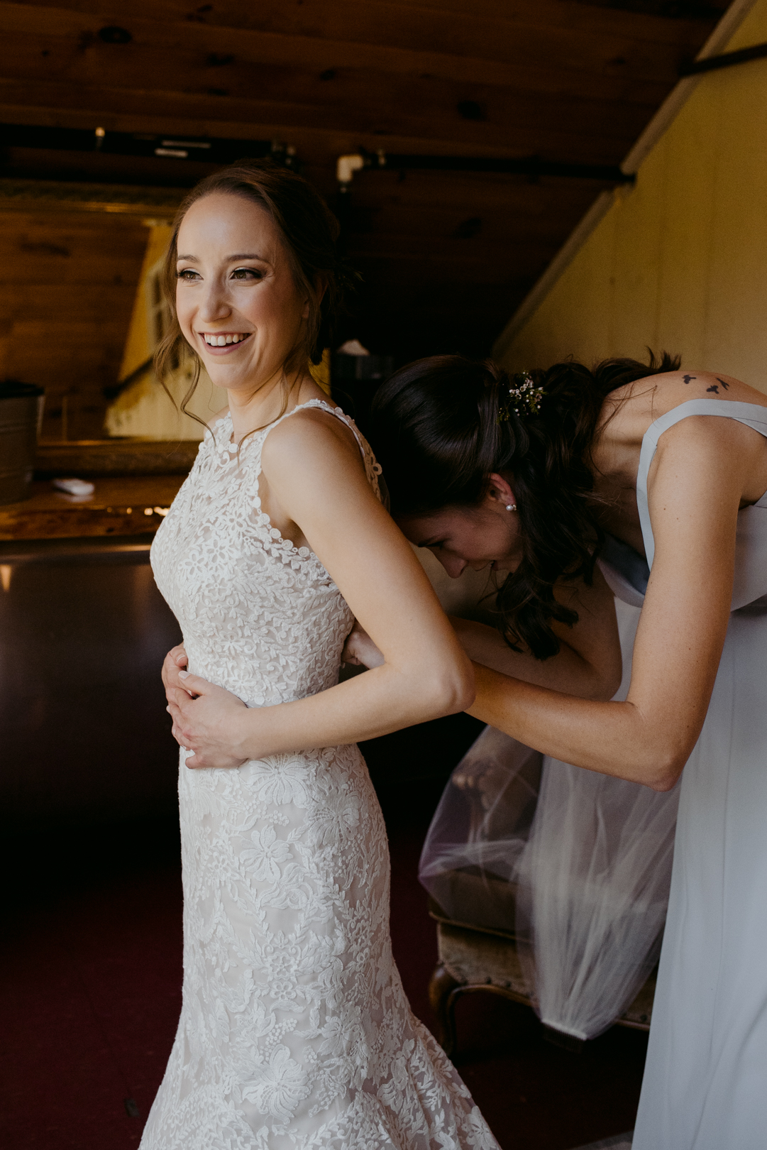 bridesmaid helping bride into her dress