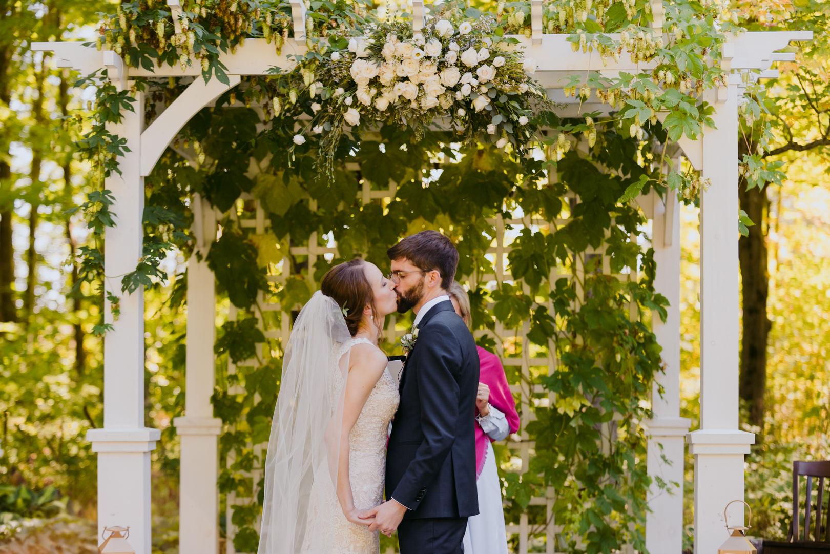 bride and groom first kiss under outdoor wedding arch
