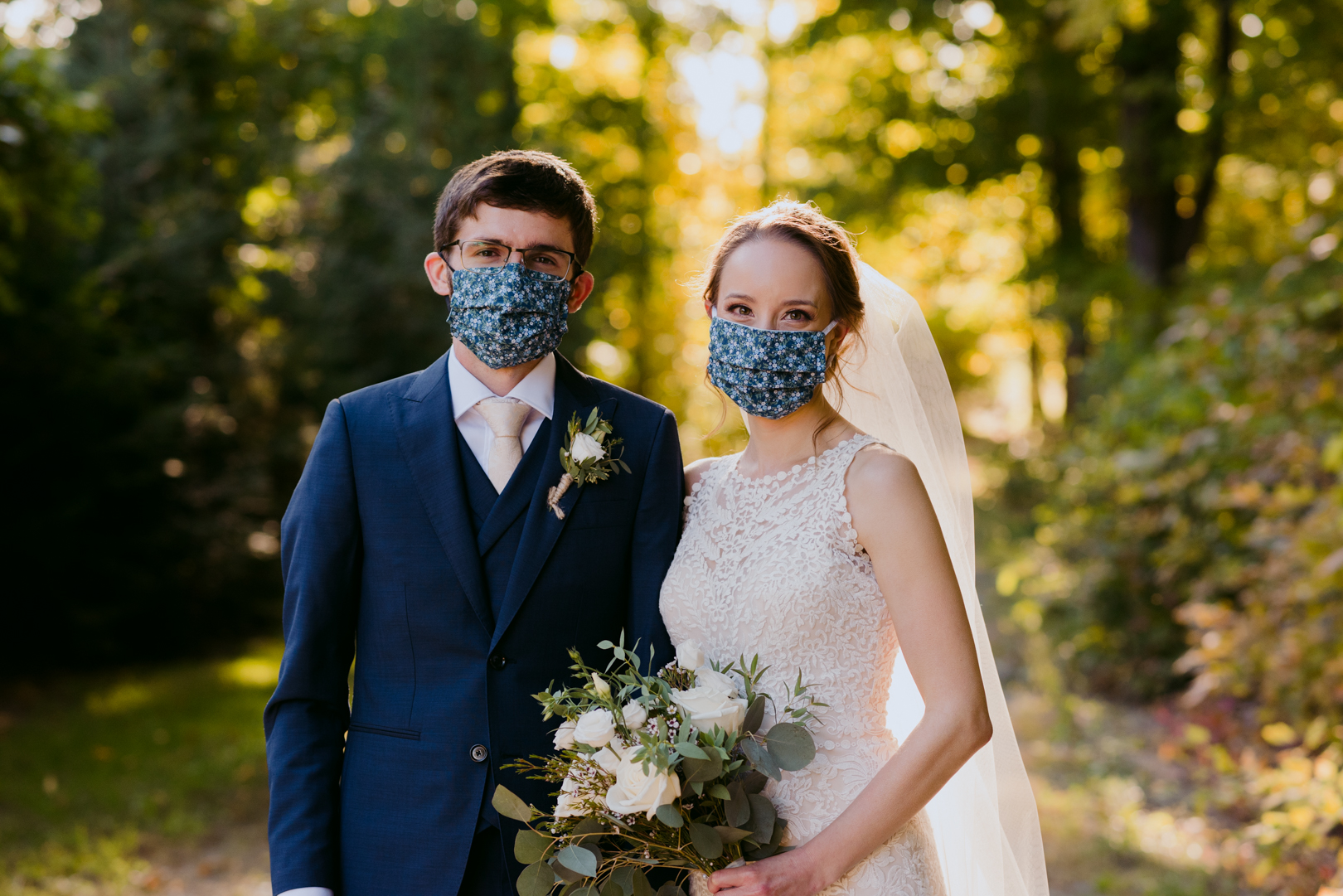 bride and groom wearing masks at sunset
