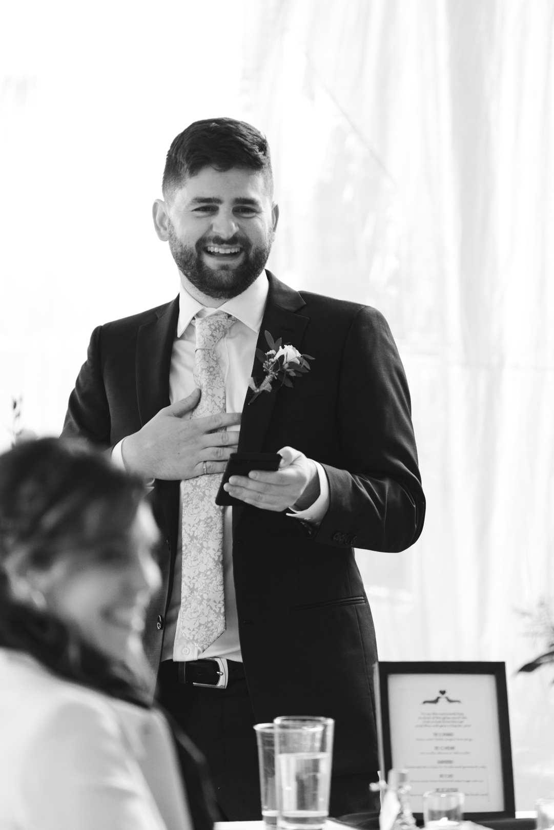 groomsman giving speech and laughing in black and white