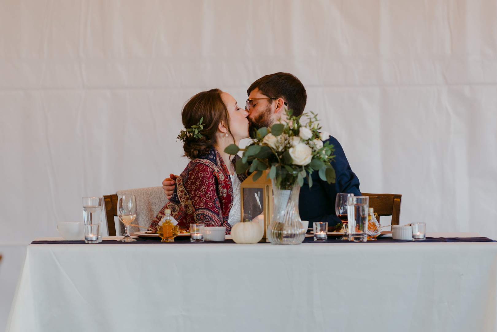 bride and groom kissing at head table during speeches