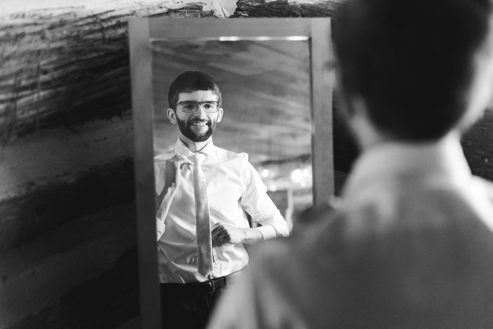 groom adjusting his tie in the mirror