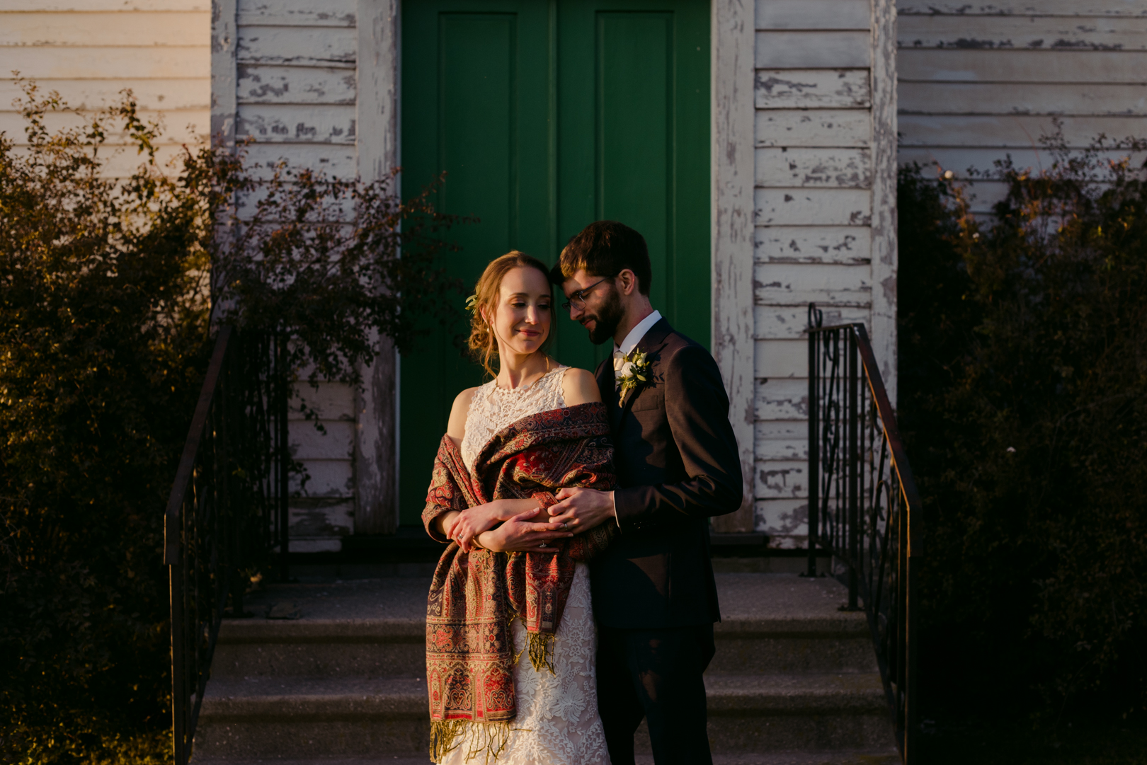 bride and groom cuddling in front of turquoise church door