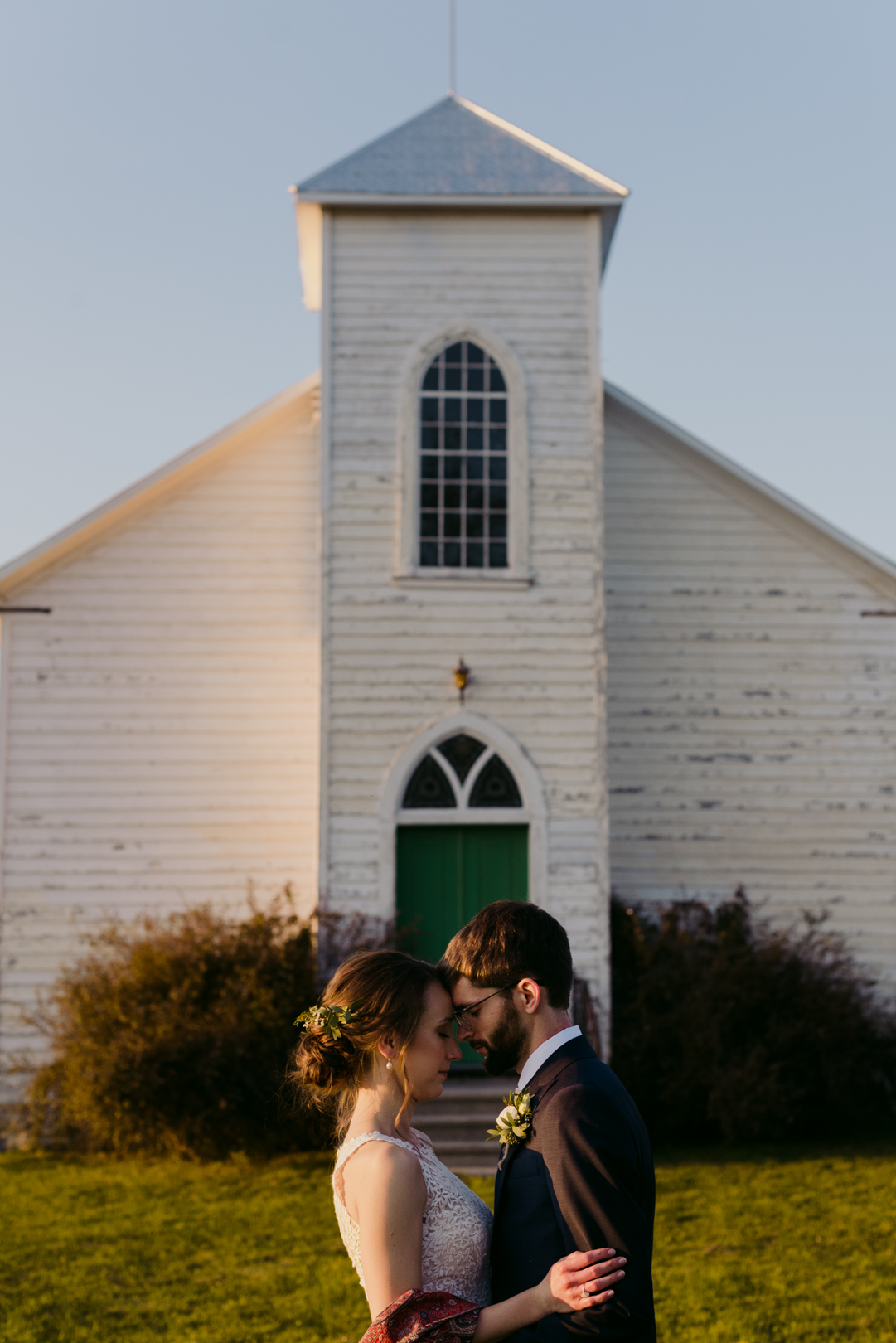 bride and groom in front of old church at sunset