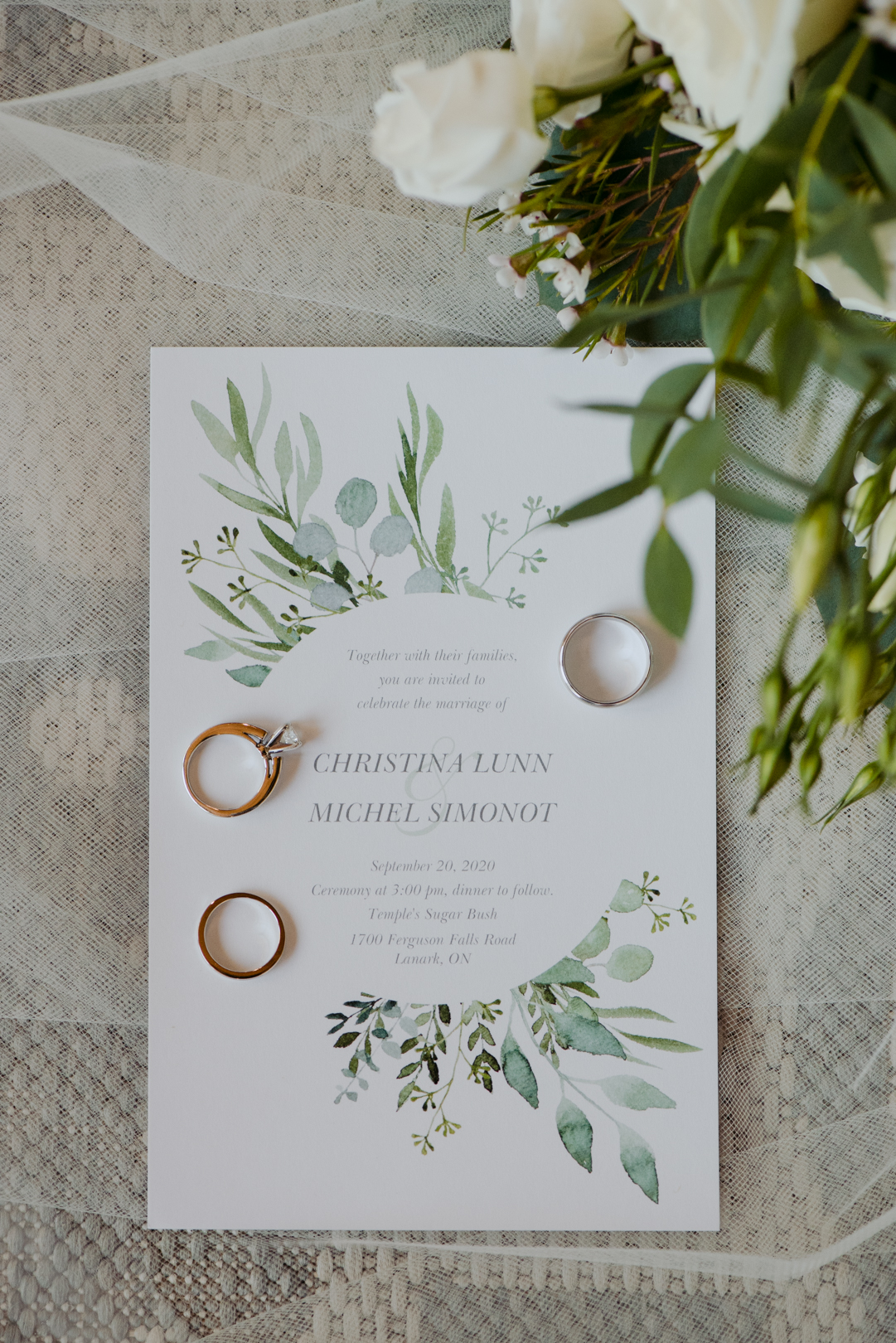flat lay of wedding invitations and rings with flowers