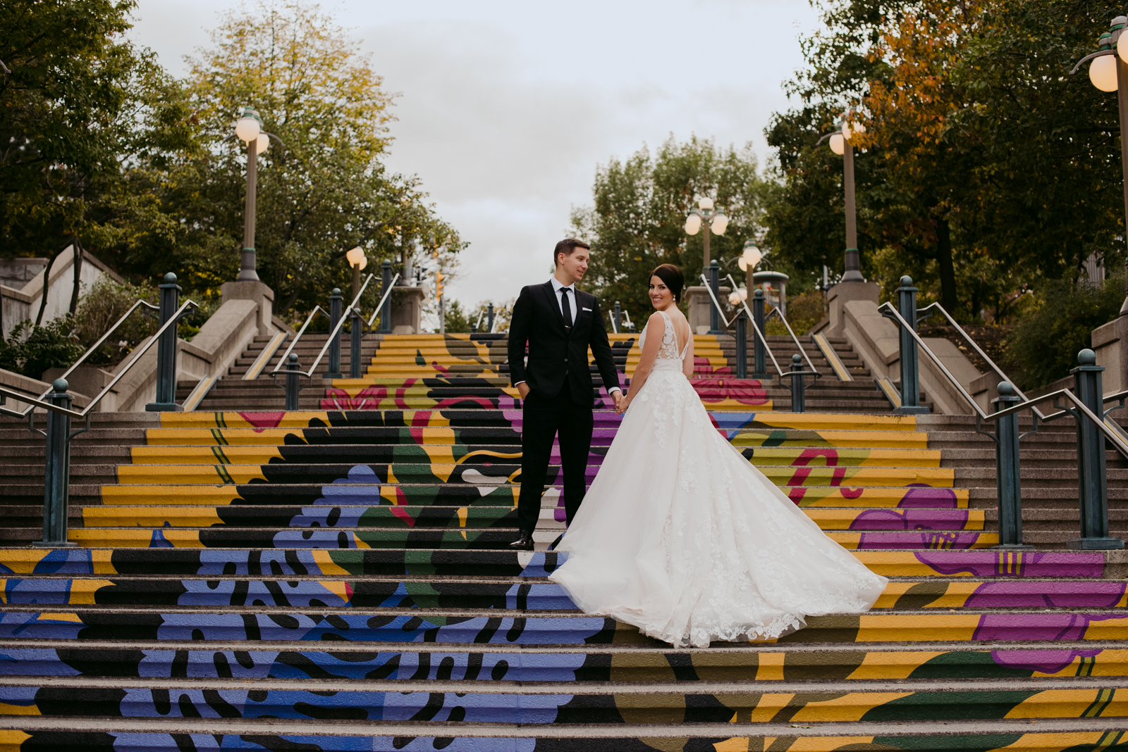 bride and groom standing on painted steps of byward market with bride's train down the steps