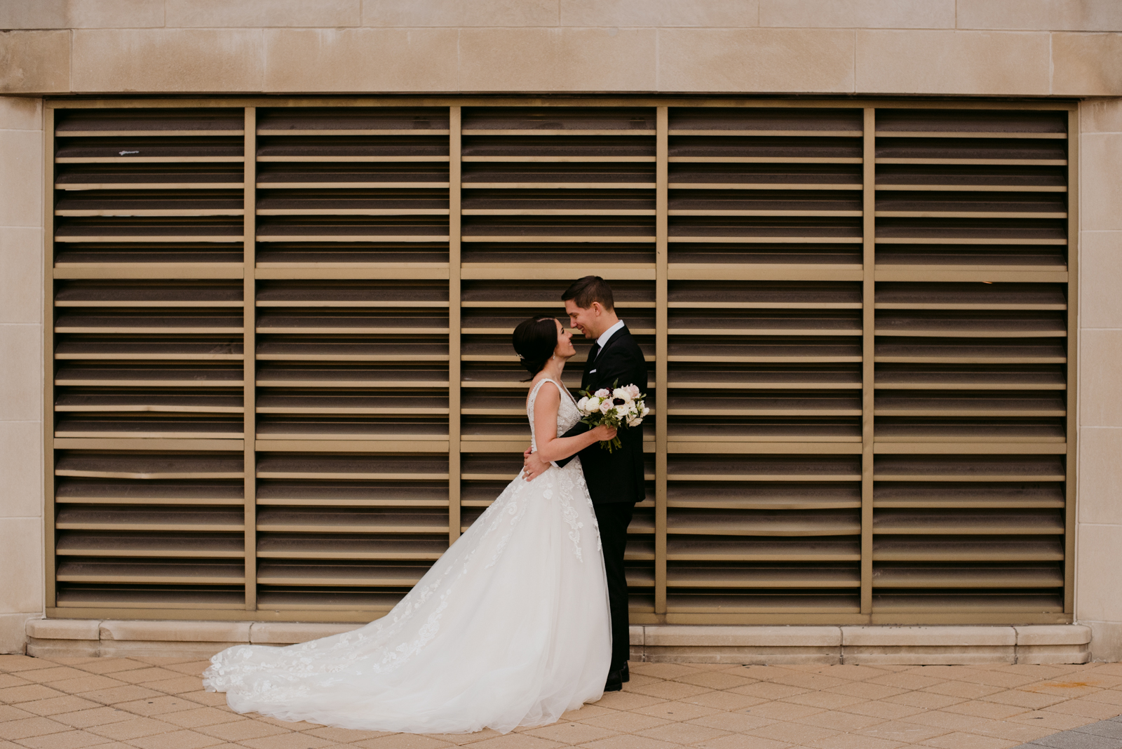 bride and groom in front of gold metal grate