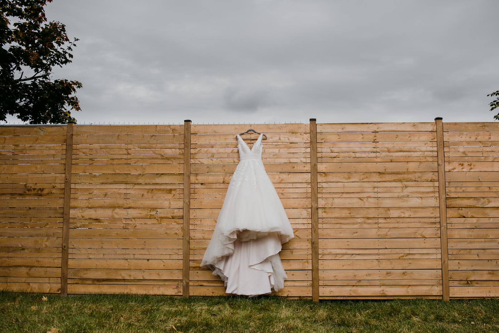 bride's dress hanging on wooden fence outside