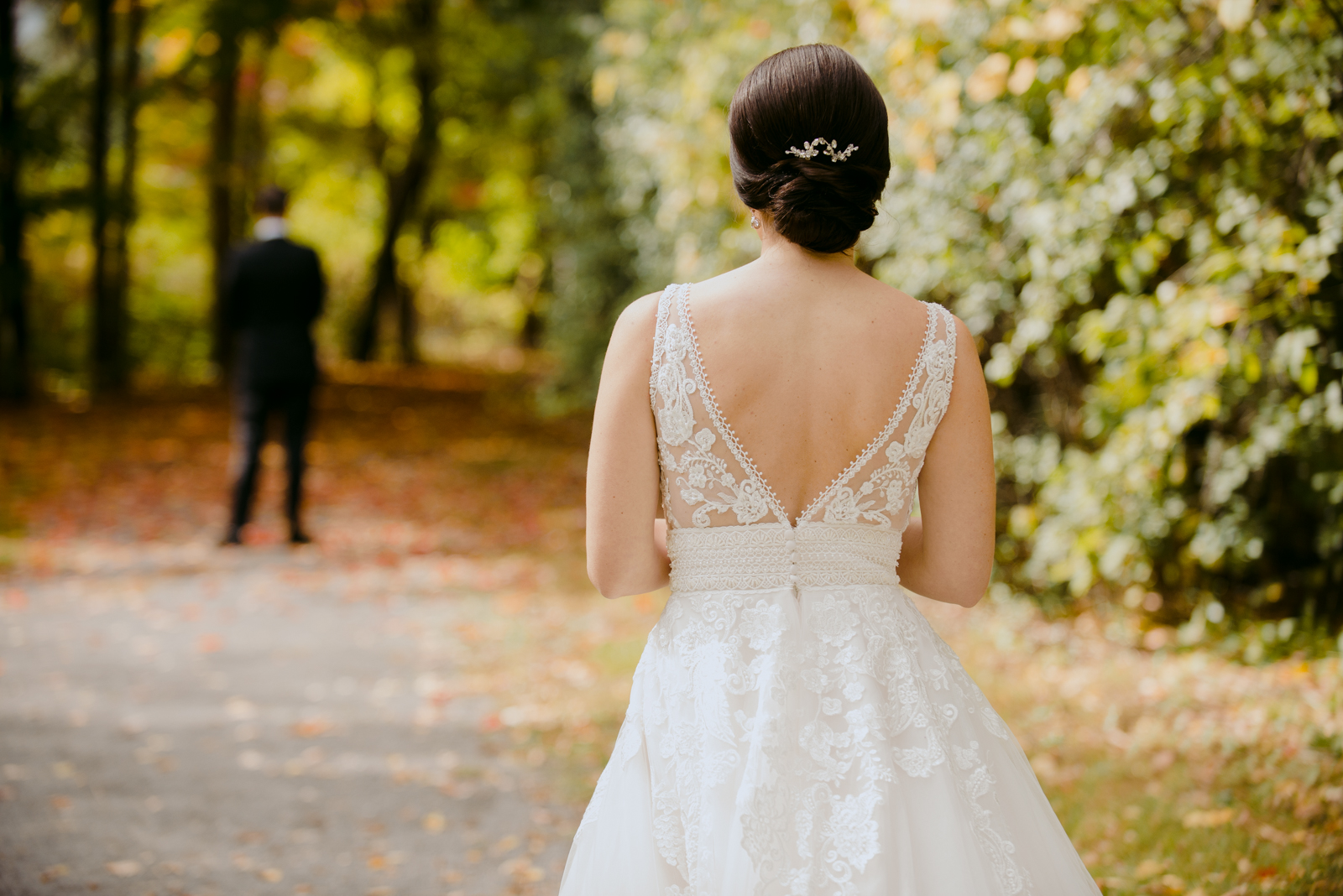 bride walking towards her groom on fall coloured path for first look