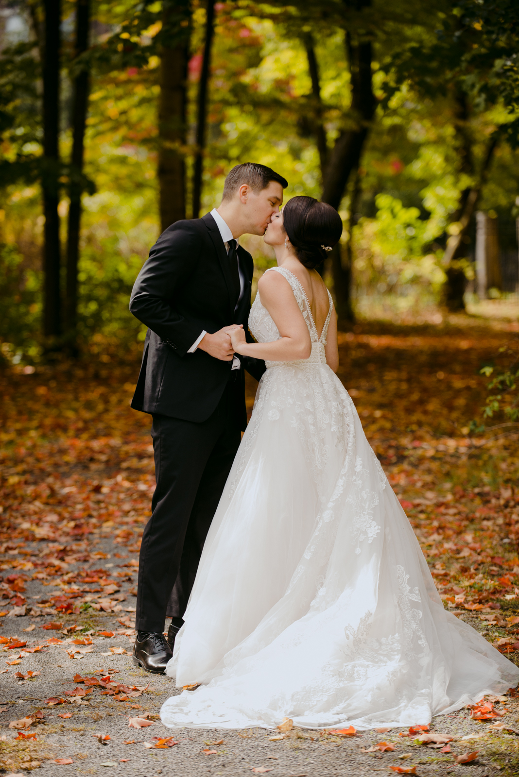 bride and groom kissing after first look on fall coloured path