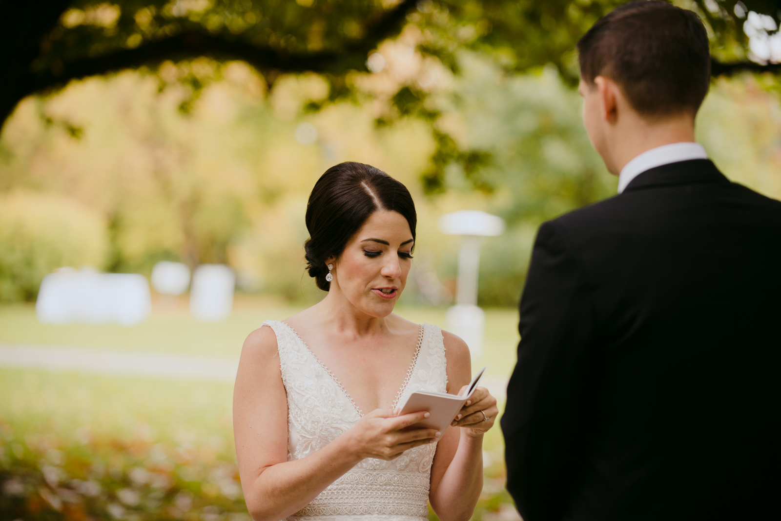 bride reading her vows from vow book during outdoor wedding ceremony