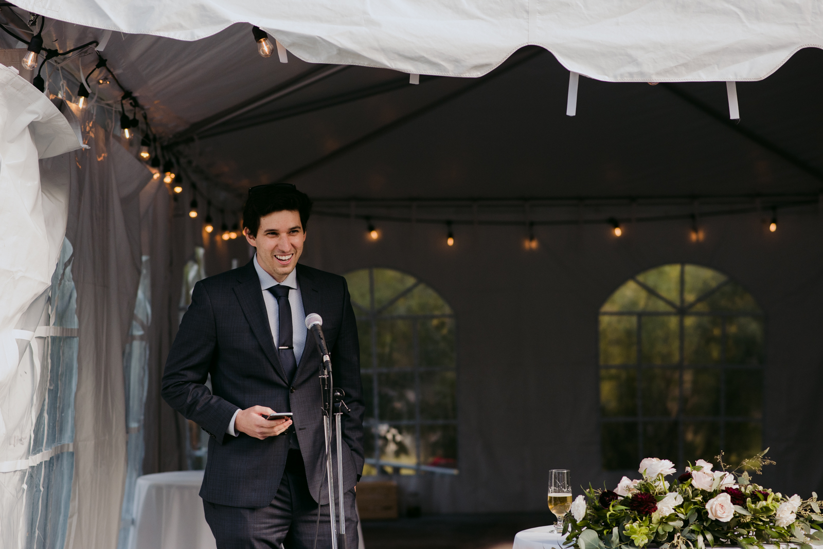groomsman giving speech at outdoor wedding reception