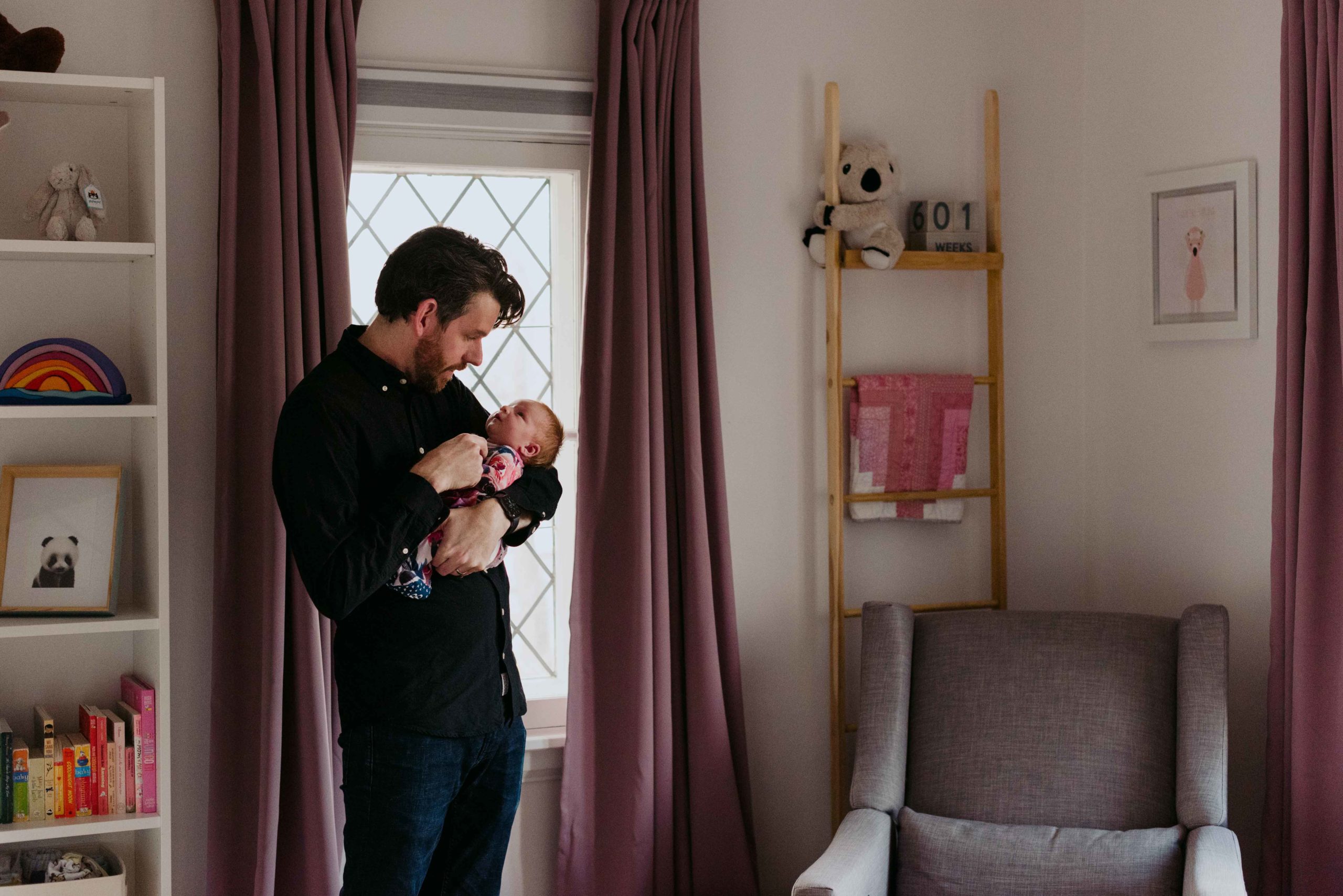 father and baby girl cuddling in pink nursery