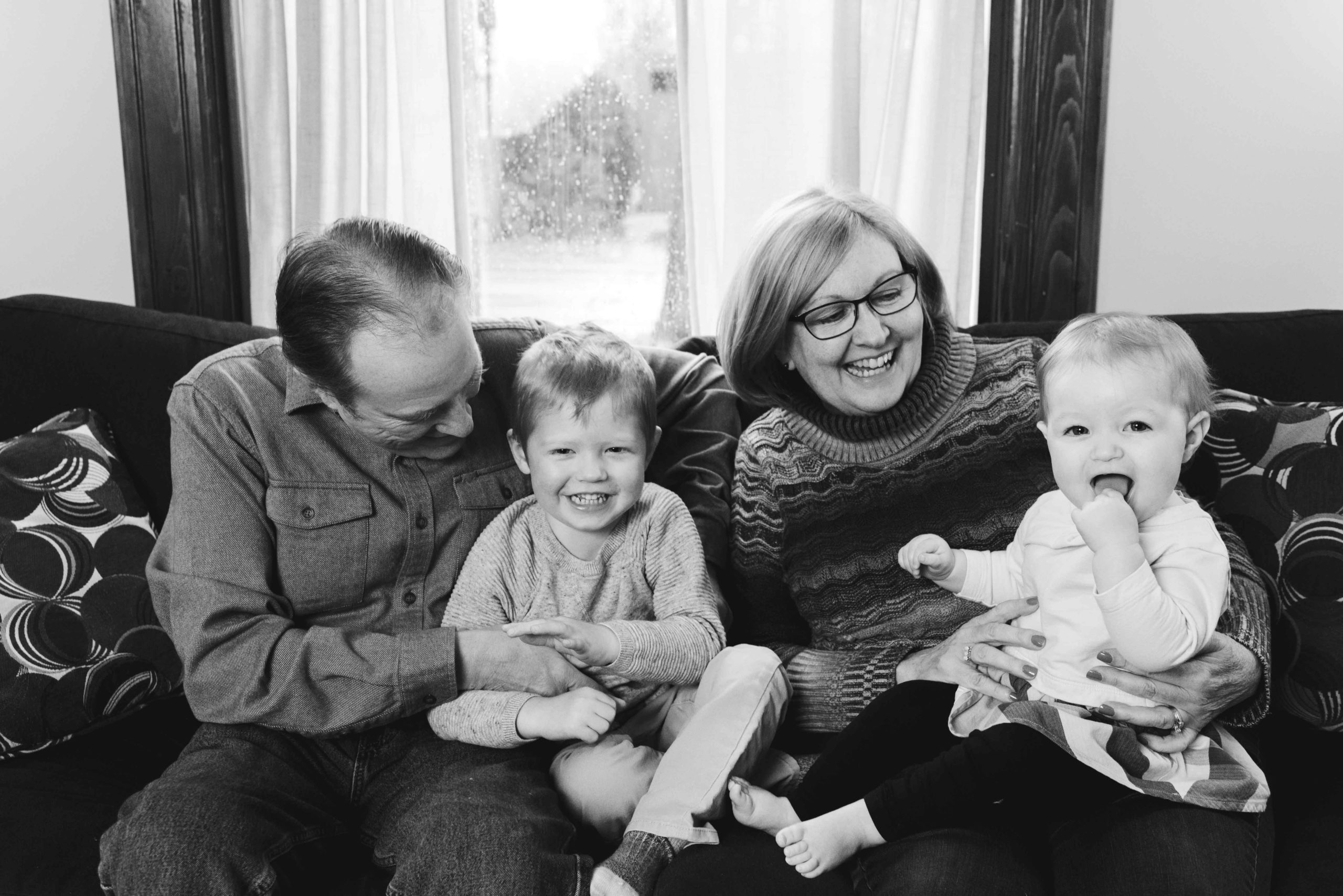 grandparents cuddling with grandkids on the couch in black and white