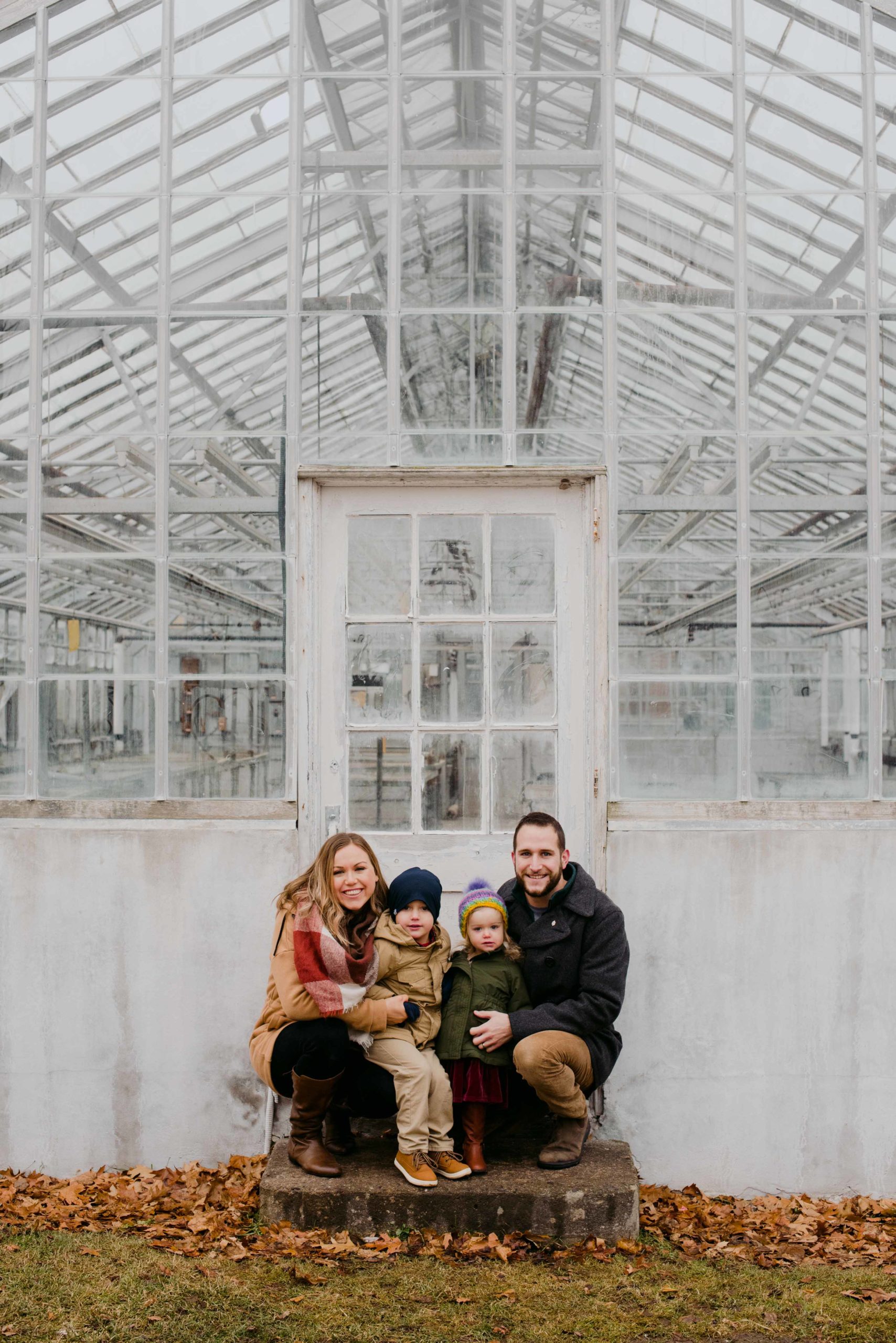 family of four in front of old white greenhouse at the experimental farm