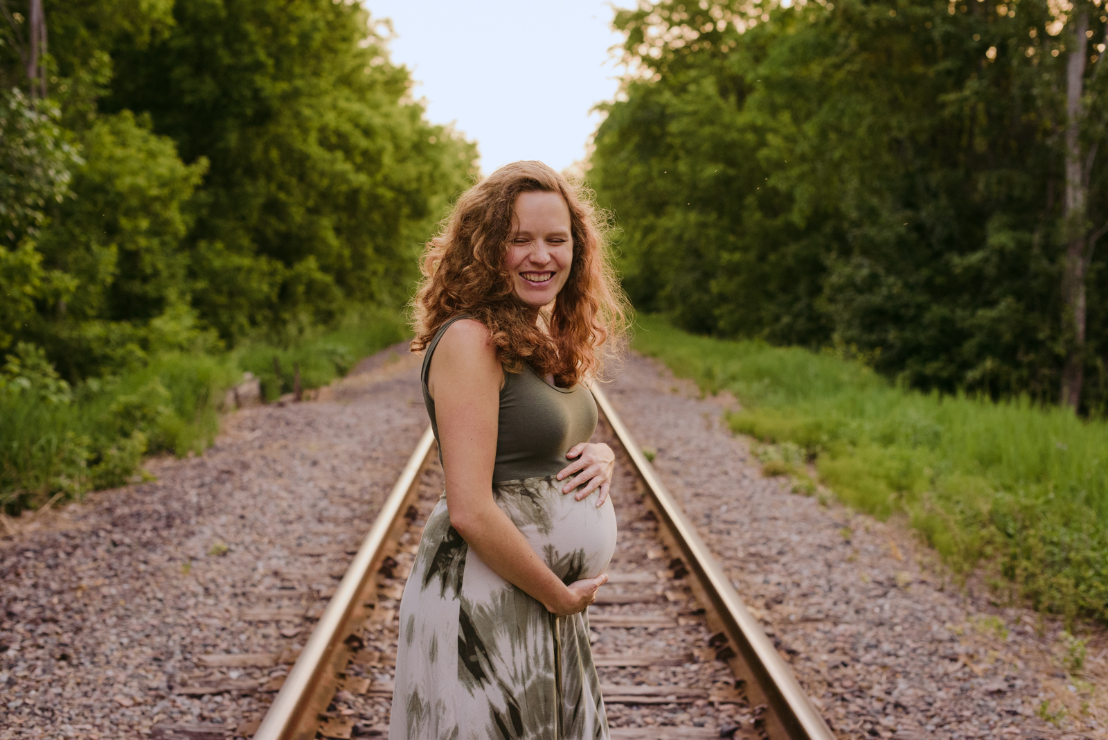 mother to be on train tracks laughing at sunset
