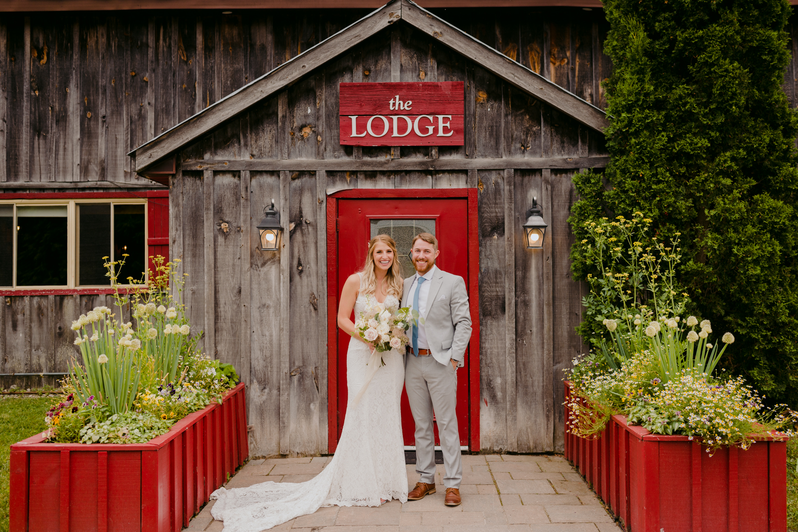 bride and groom standing in front of the lodge at Strathmere smiling at the camera