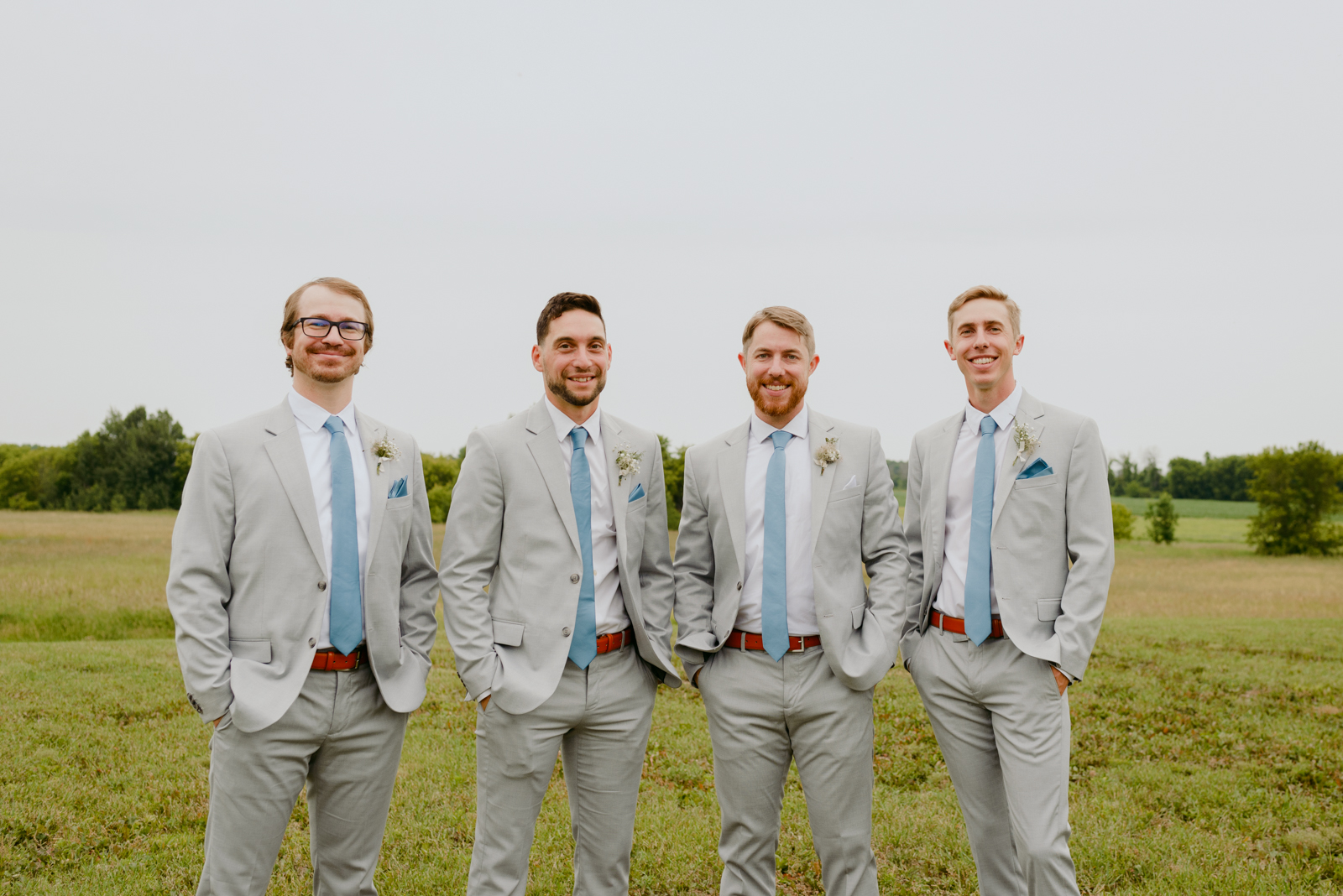 groom and groomsmen in grey and blue in a field at Strathmere
