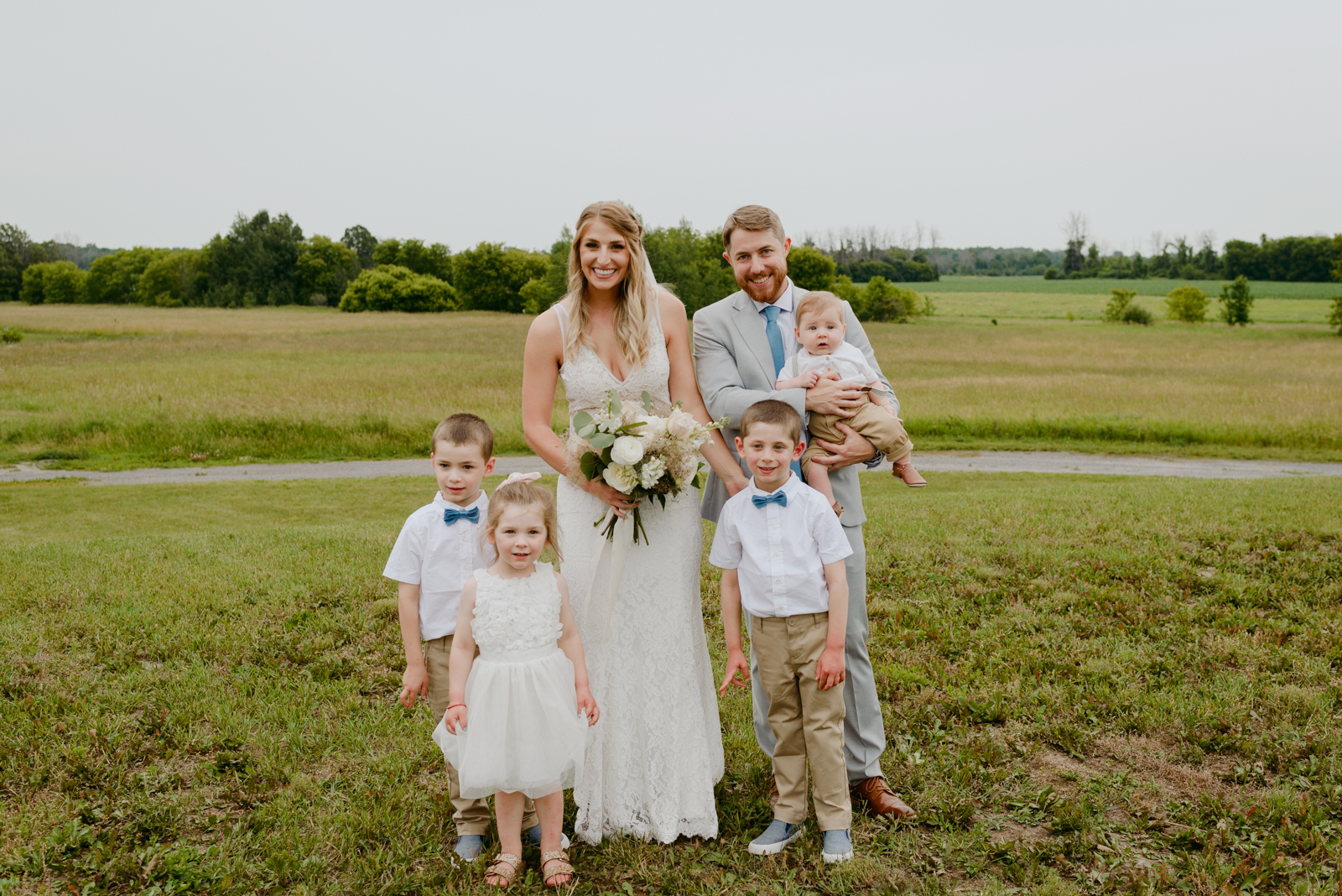bride and groom with flower girl and ring bearer in a field at Strathmere