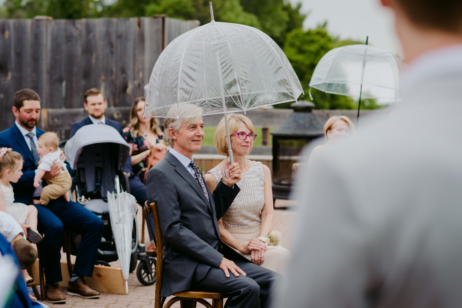 groom's parents underneath umbrella during rainy wedding ceremony