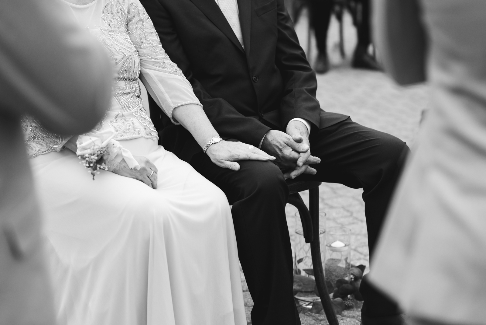 mother of the bride with her hand on father's lap during wedding ceremony