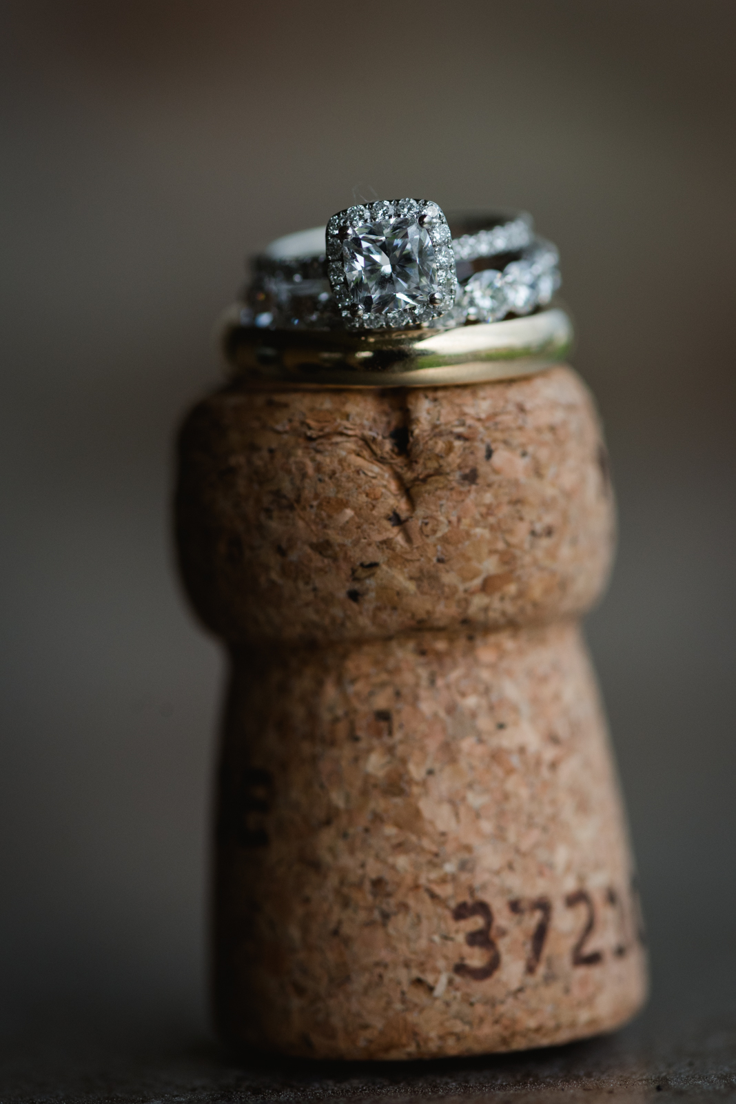 wedding rings stacked on top of champagne cork