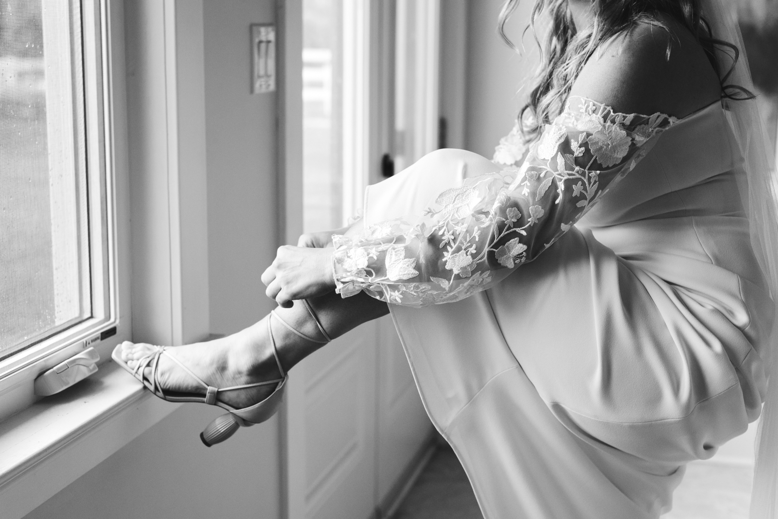 bride tying her shoes in in black and white