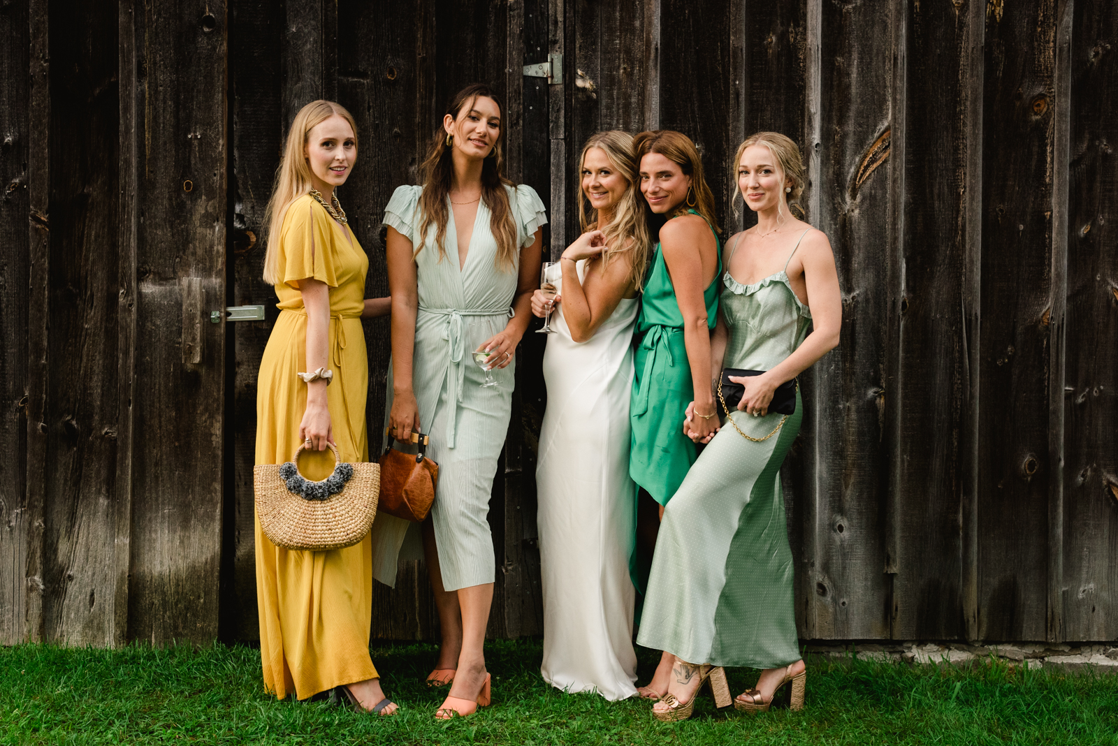 bride and bridesmaids in different shades against old barn