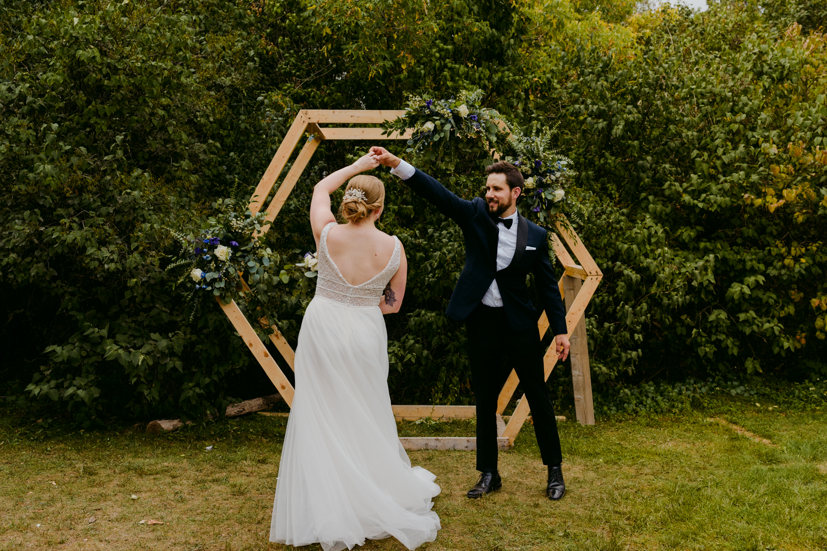 groom twirling bride in front of wooden hexagon