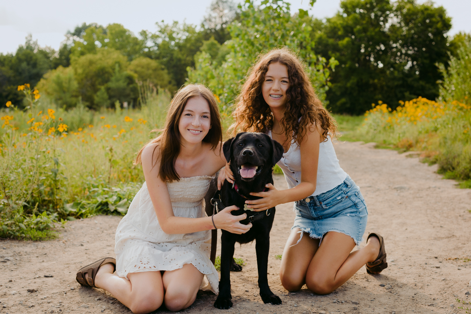 two sisters with black lab outdoors