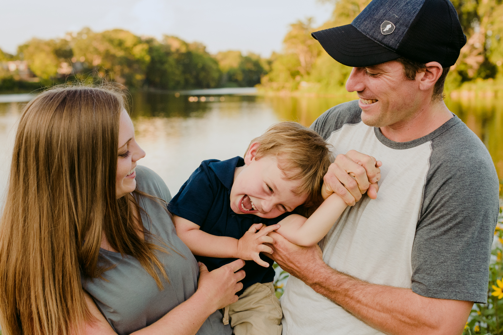 parents and son laughing and smiling by the water