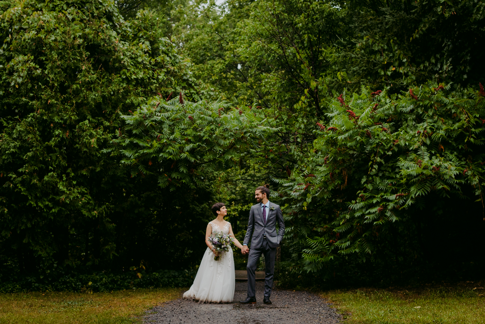 bride and groom standing in front of red sumac trees