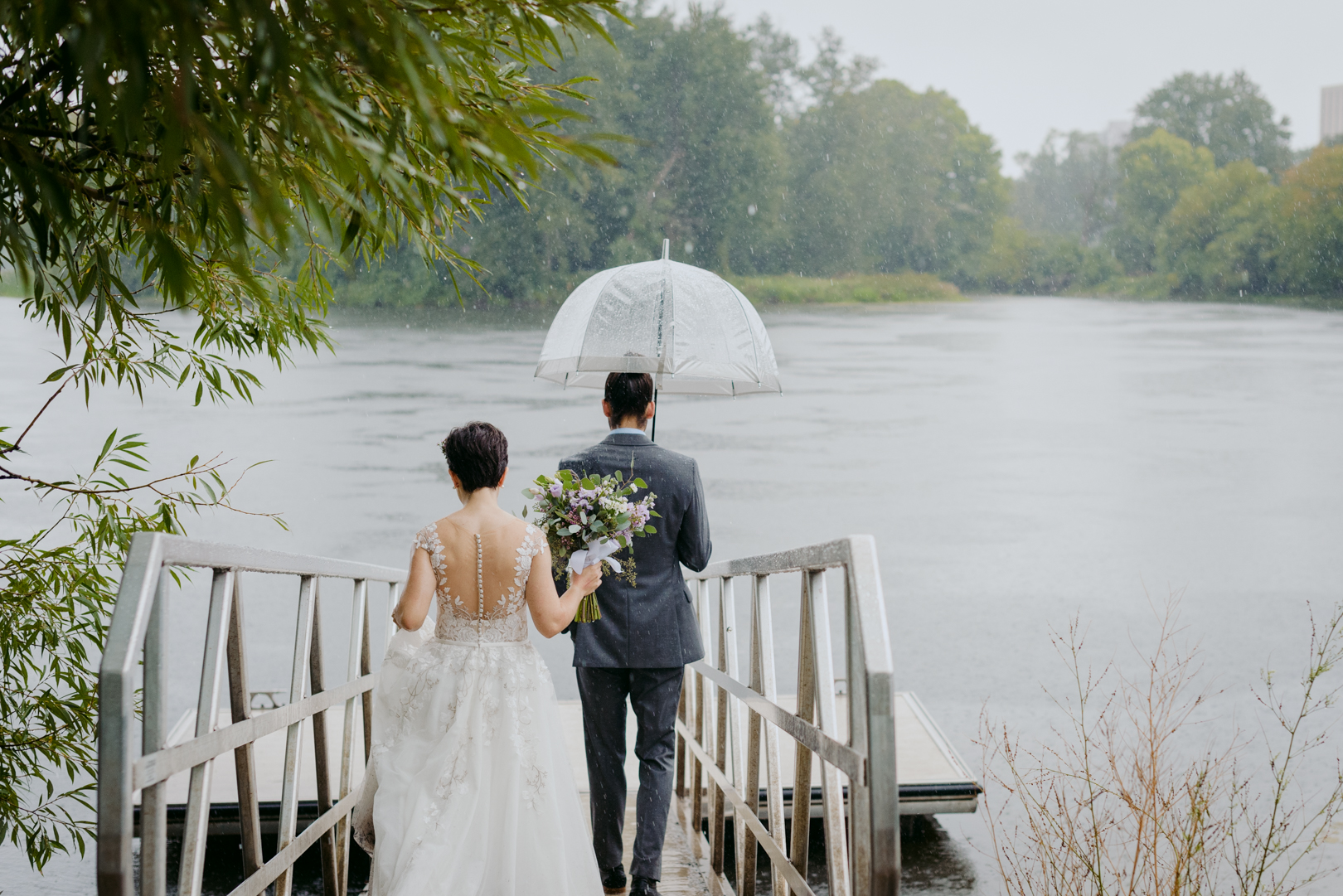 bride and groom walking down to dock on a rainy day