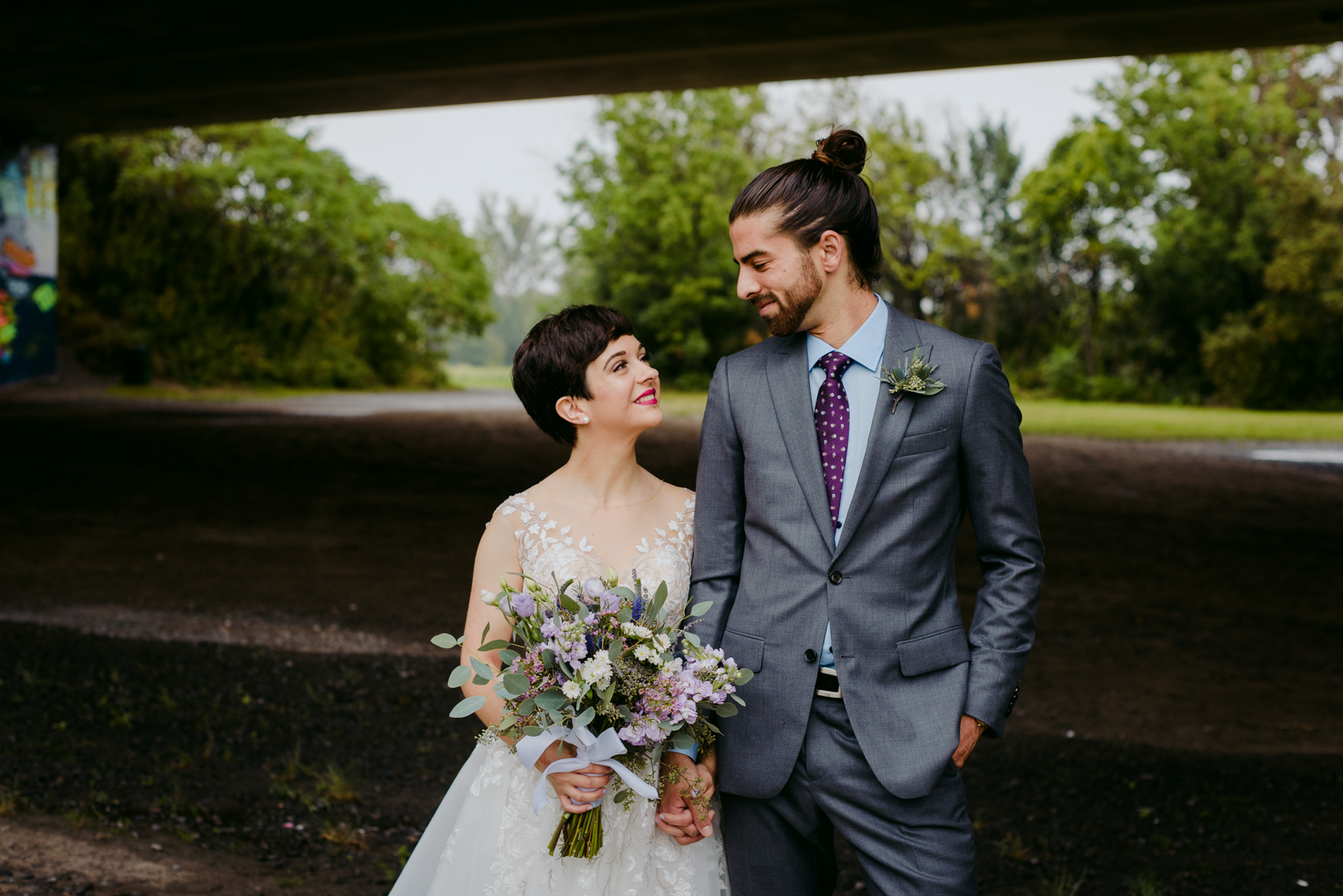 bride and groom smiling at each other underneath a bridge