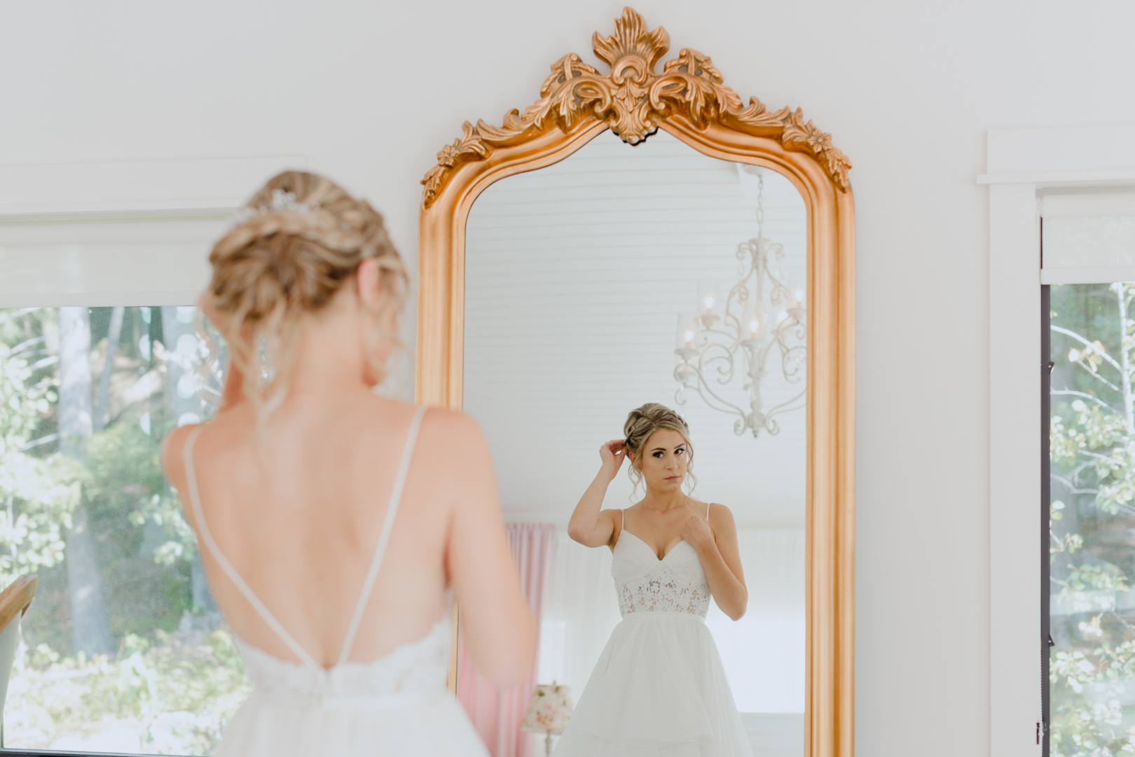 bride fixing her hair in the mirror in her wedding dress