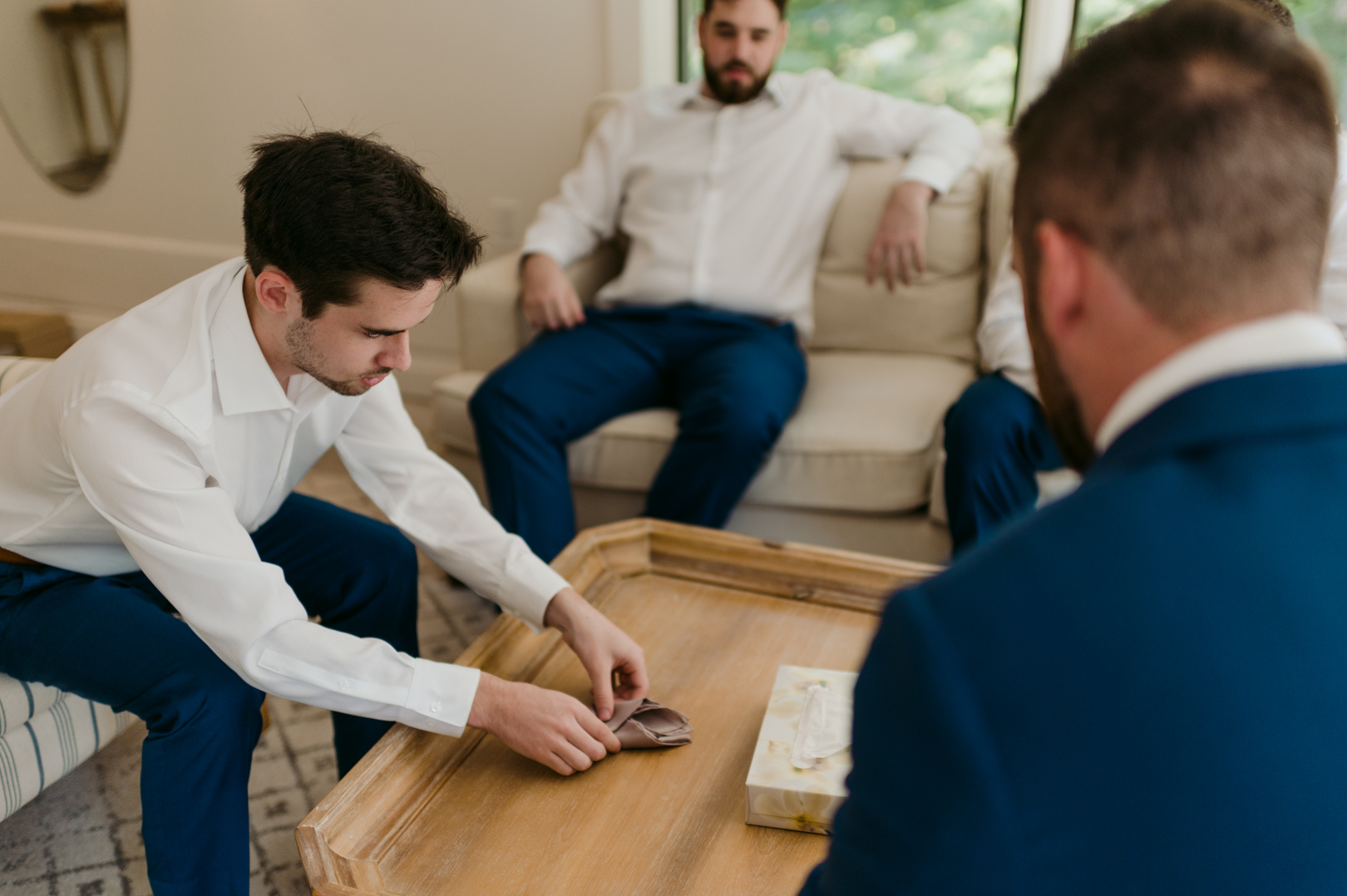 groomsmen folding pocket square while getting ready