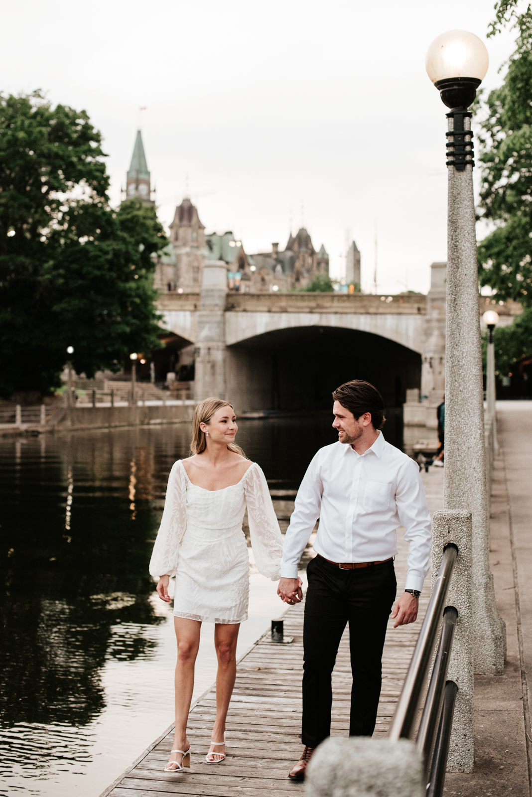 engaged couple holding hands by the rideau canal locks at sunset