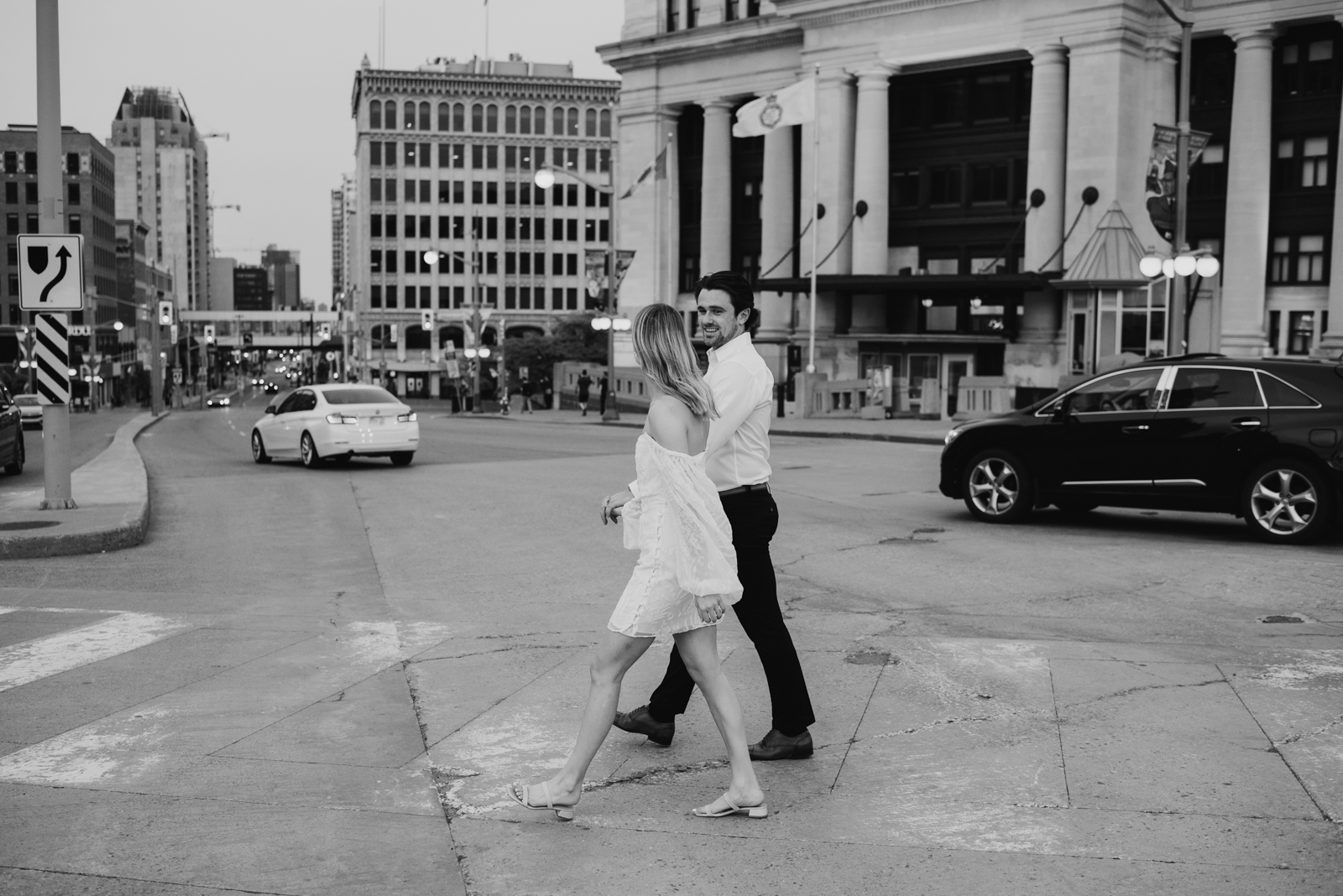engaged couple crossing wellington street in downtown ottawa in black and white